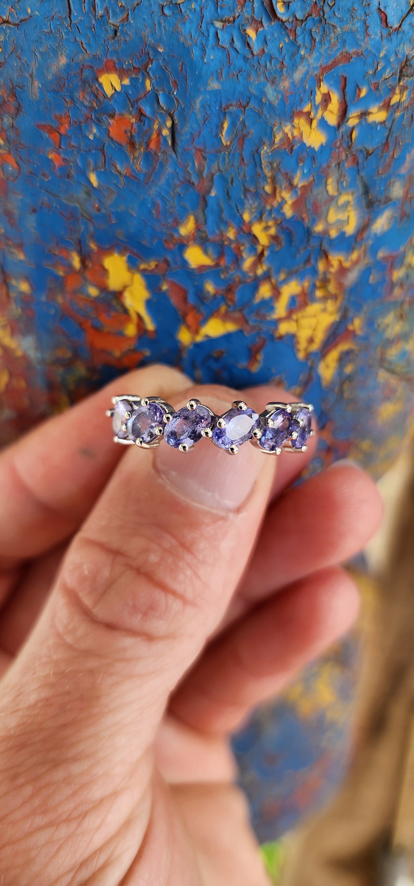 This exquisite sterling silver half-eternity ring showcases six oval faceted-cut Tanzanite gemstones, each carefully set in a four-claw setting for maximum visibility and brilliance.