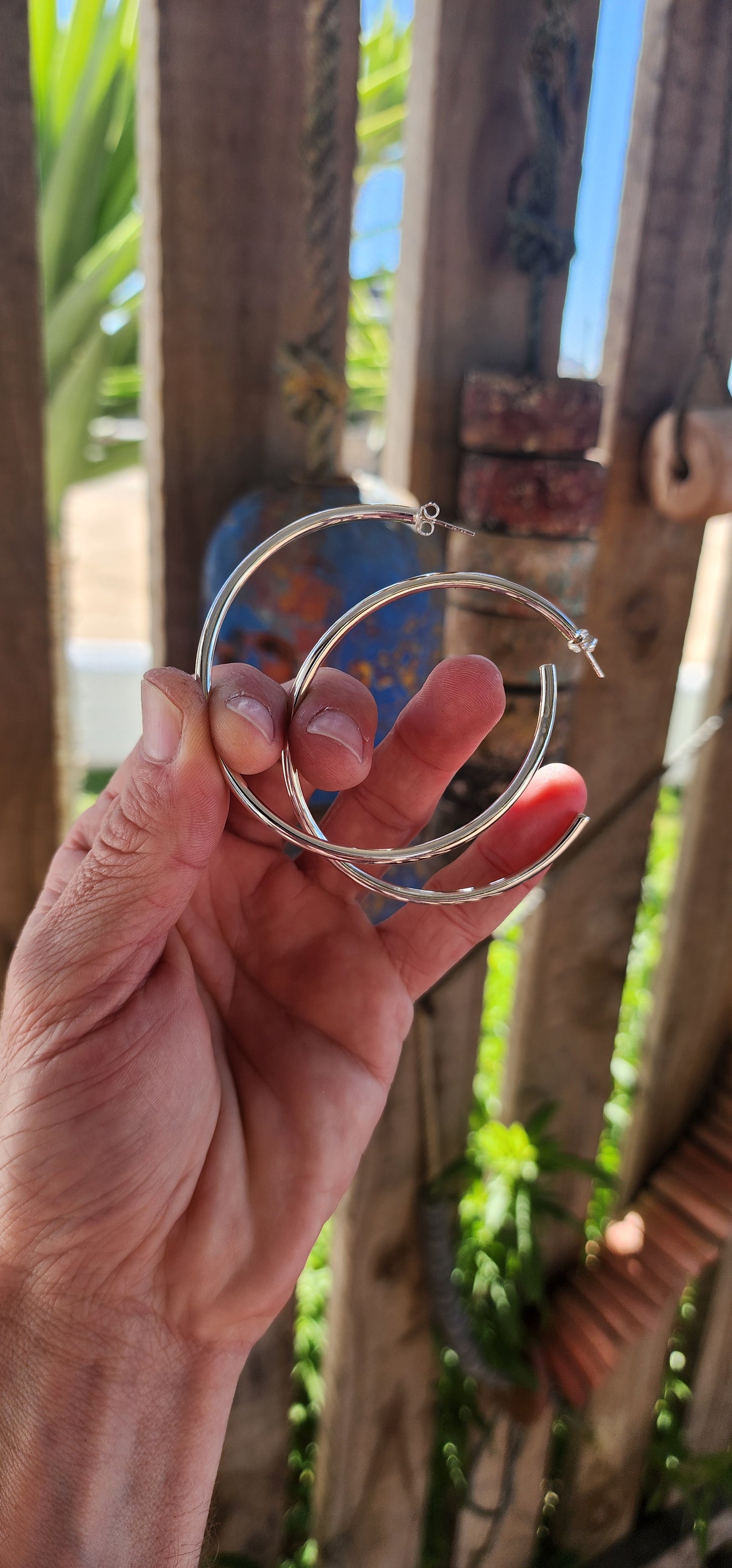 These oversized sterling silver hoop earrings boast a bold, tubular design with a clean and minimalist aesthetic.