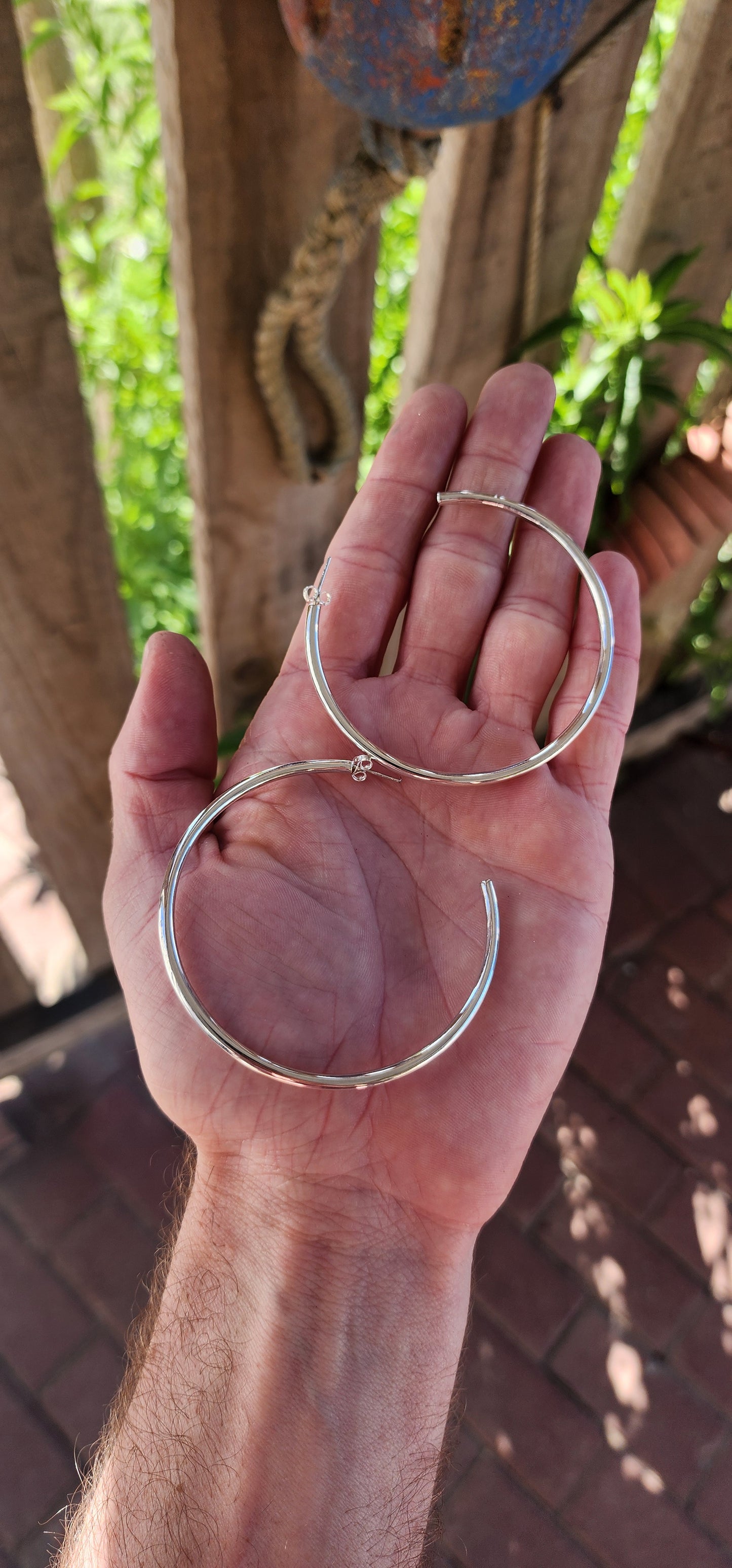 These oversized sterling silver hoop earrings boast a bold, tubular design with a clean and minimalist aesthetic.