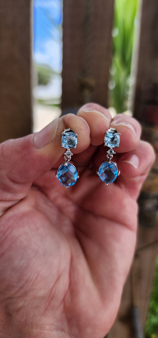 These sterling silver drop earrings are a masterful composition of elegance and radiance, showcasing the breathtaking beauty of blue topaz gemstones.