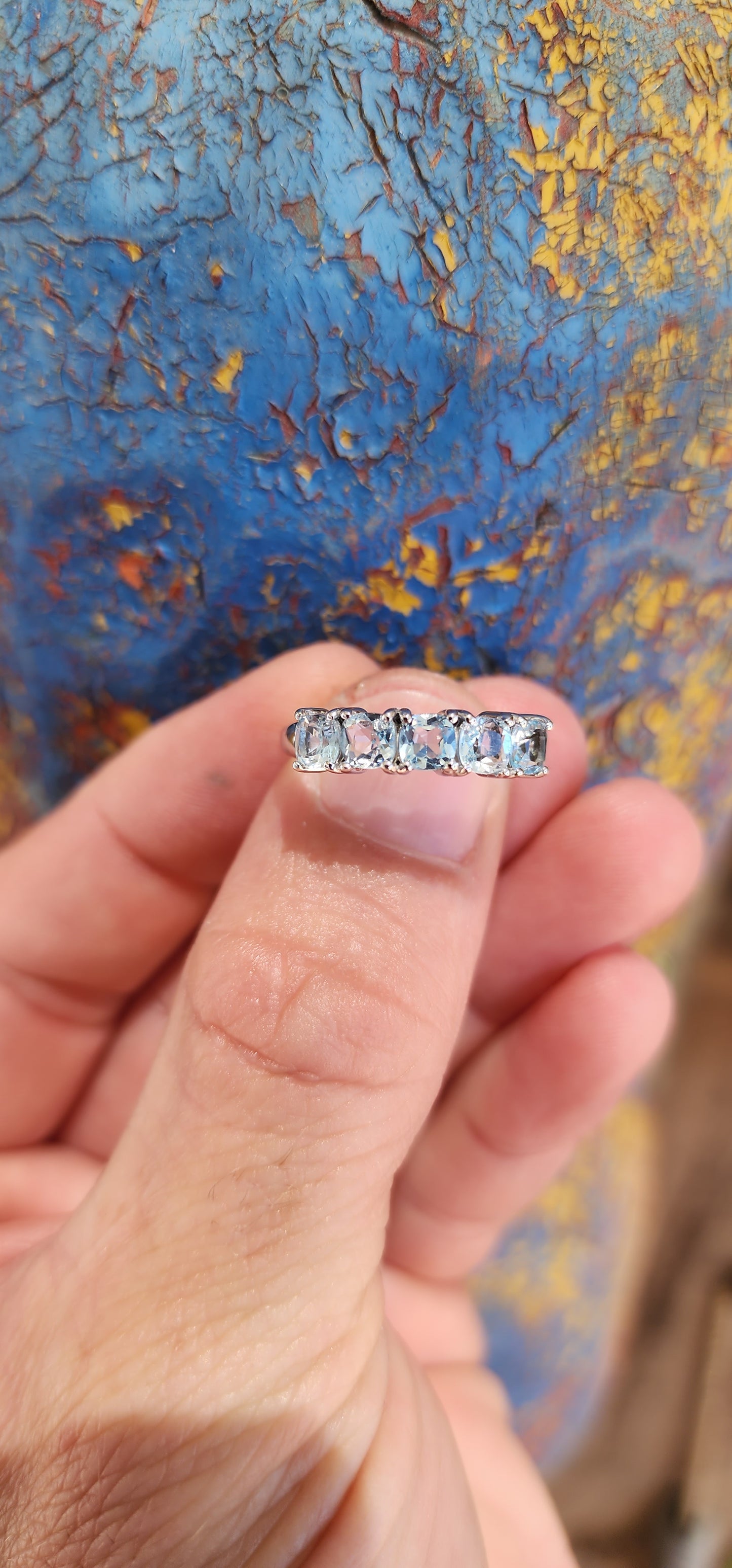 This beautiful sterling silver half-eternity ring features five cushion-cut sky-blue topaz gemstones that are securely set in prong settings.