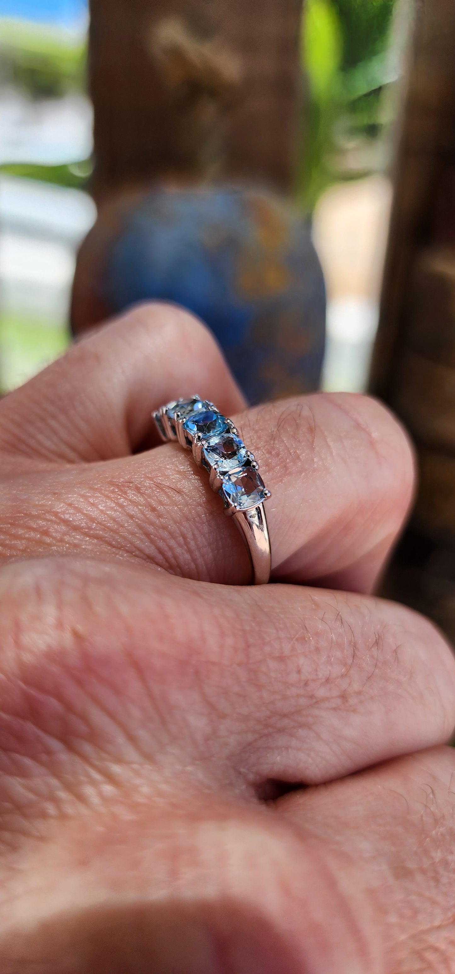 This beautiful sterling silver half-eternity ring features five cushion-cut sky-blue topaz gemstones that are securely set in prong settings.