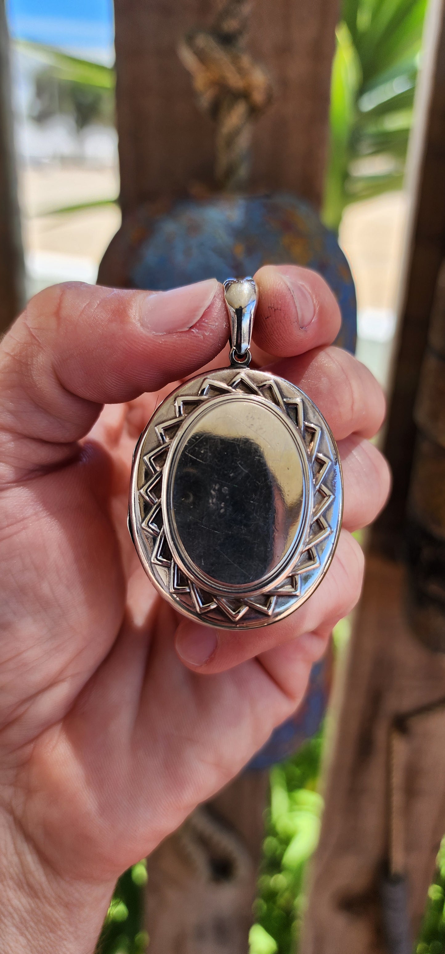 This large sized locket is a beautiful example of Victorian-era craftsmanship, designed in a sterling silver oval shape with a striking sunburst pattern encircling the center on both sides.