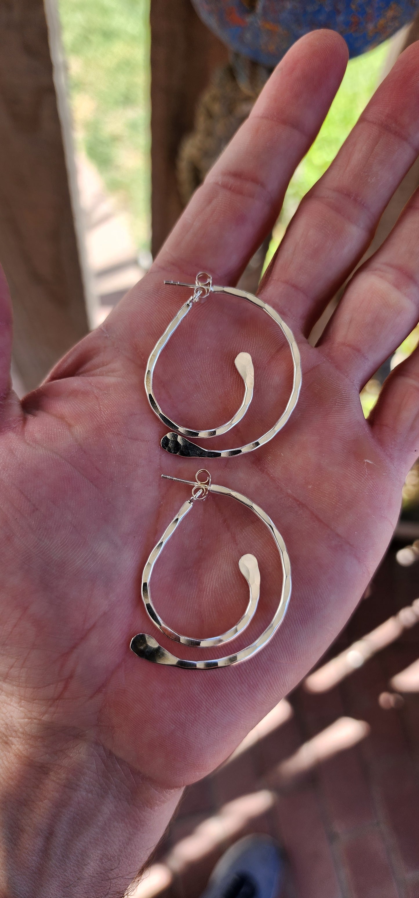 These earrings are a brilliant fusion of contemporary artistry and optical illusion! Crafted from hammered sterling silver, they feature an intriguing twisted double-half hoop design that plays with depth and dimension.