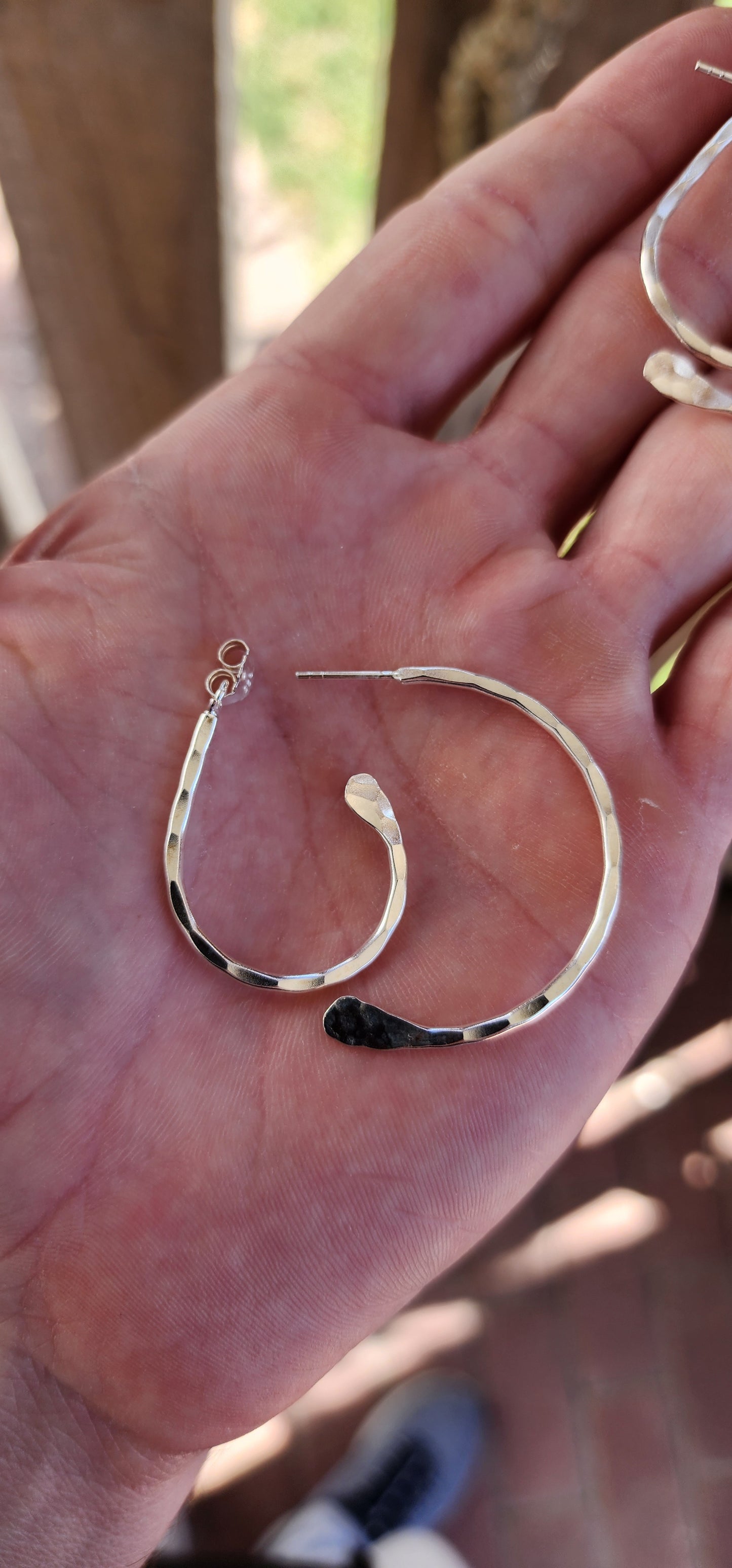 These earrings are a brilliant fusion of contemporary artistry and optical illusion! Crafted from hammered sterling silver, they feature an intriguing twisted double-half hoop design that plays with depth and dimension.