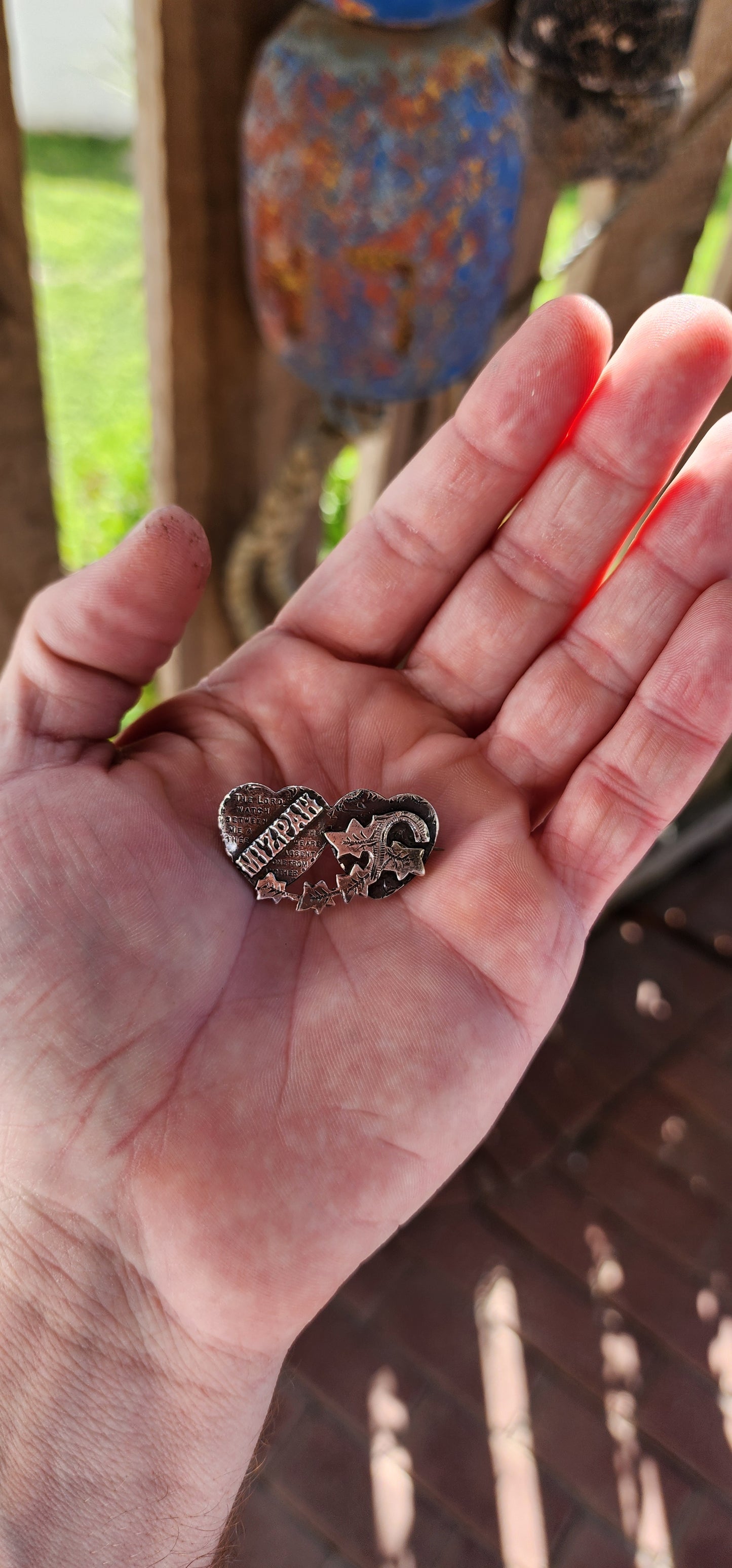This antique Victorian Mizpah brooch is a finely crafted sentimental jewelry piece, made from solid sterling silver, and designed in the shape of two interlocking hearts.
