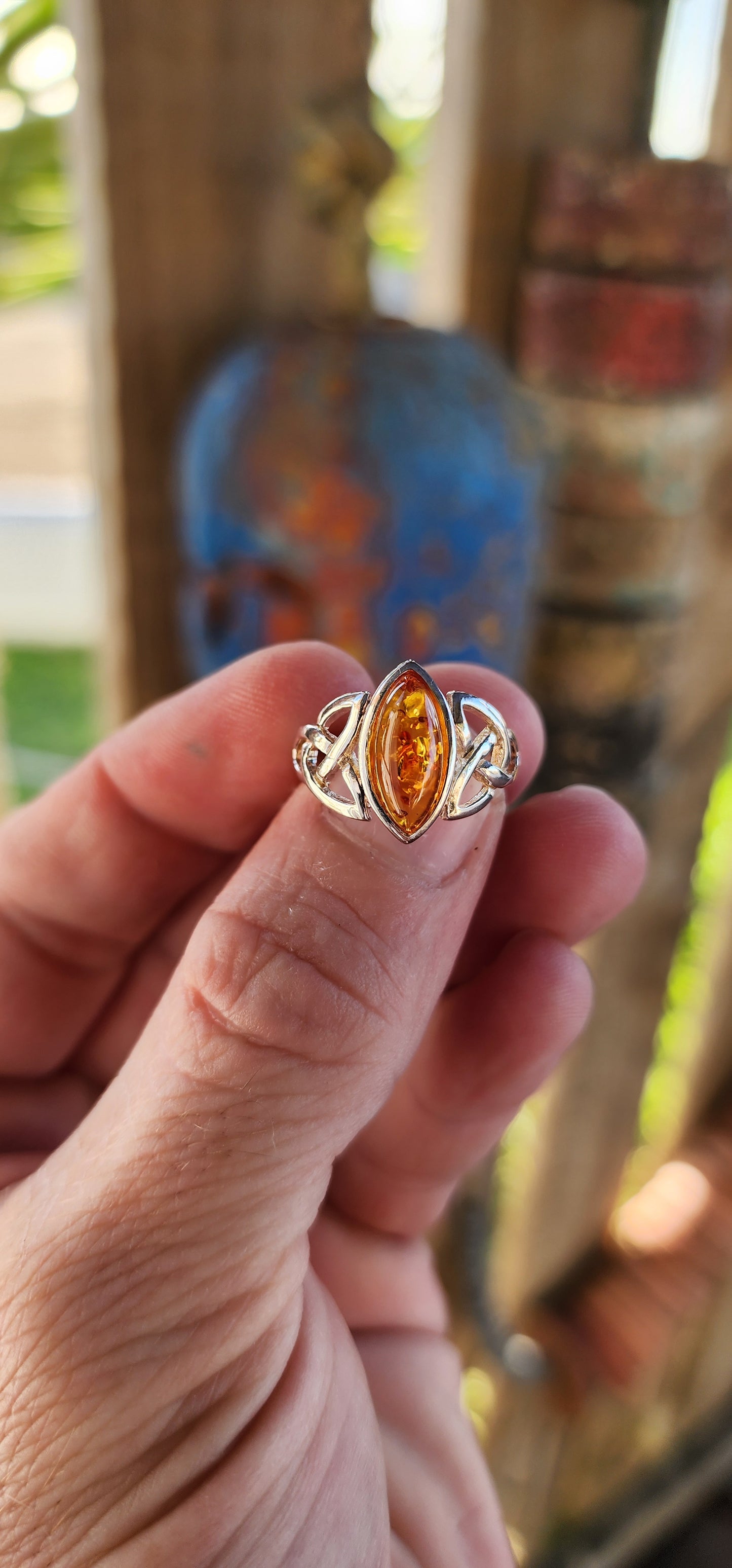 This sterling silver ring is a masterpiece of both elegance and symbolism, its design rooted in ancient Celtic tradition. At the heart of the piece rests a marquise-cut Baltic amber cabochon, its golden depths shimmering like liquid sunlight.
