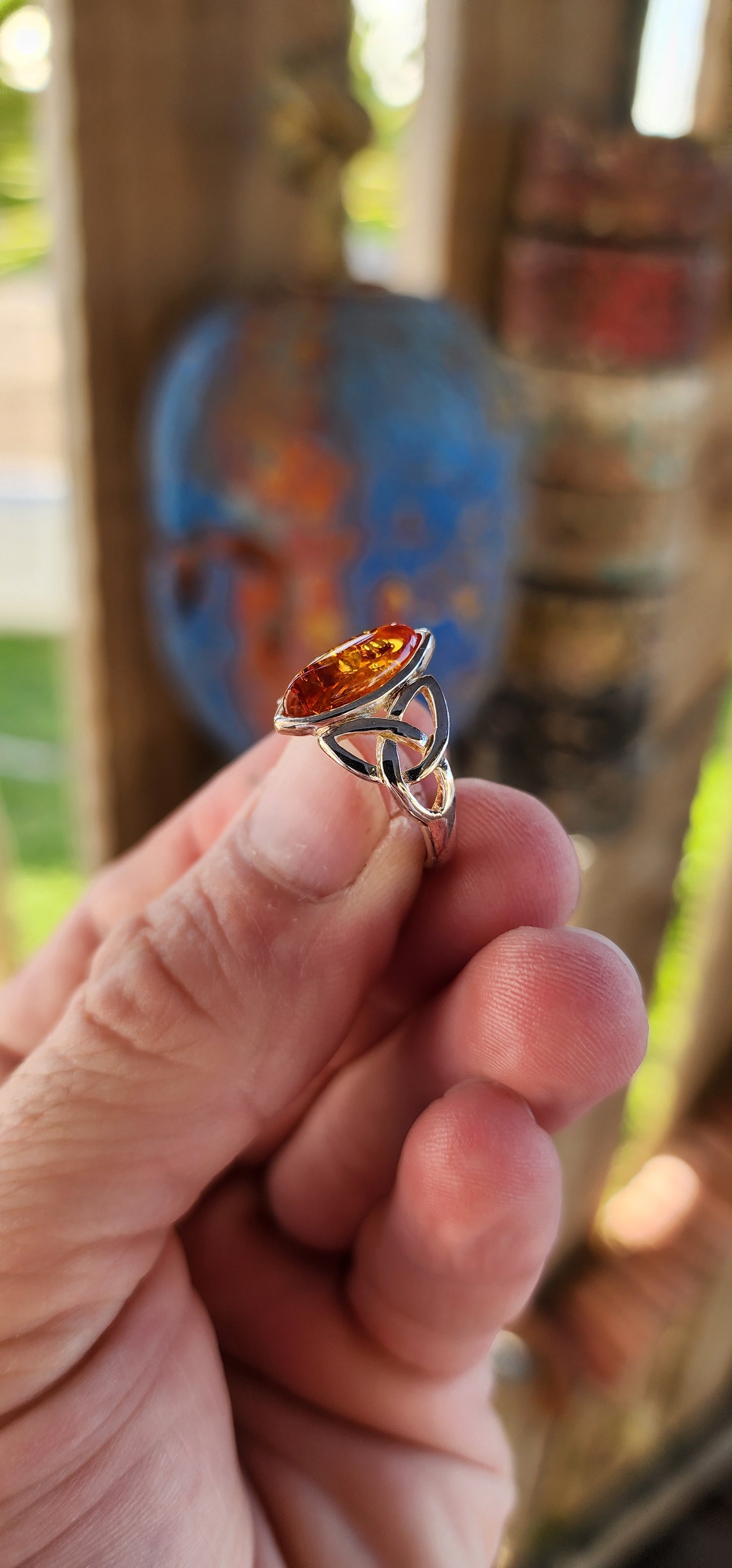 This sterling silver ring is a masterpiece of both elegance and symbolism, its design rooted in ancient Celtic tradition. At the heart of the piece rests a marquise-cut Baltic amber cabochon, its golden depths shimmering like liquid sunlight.