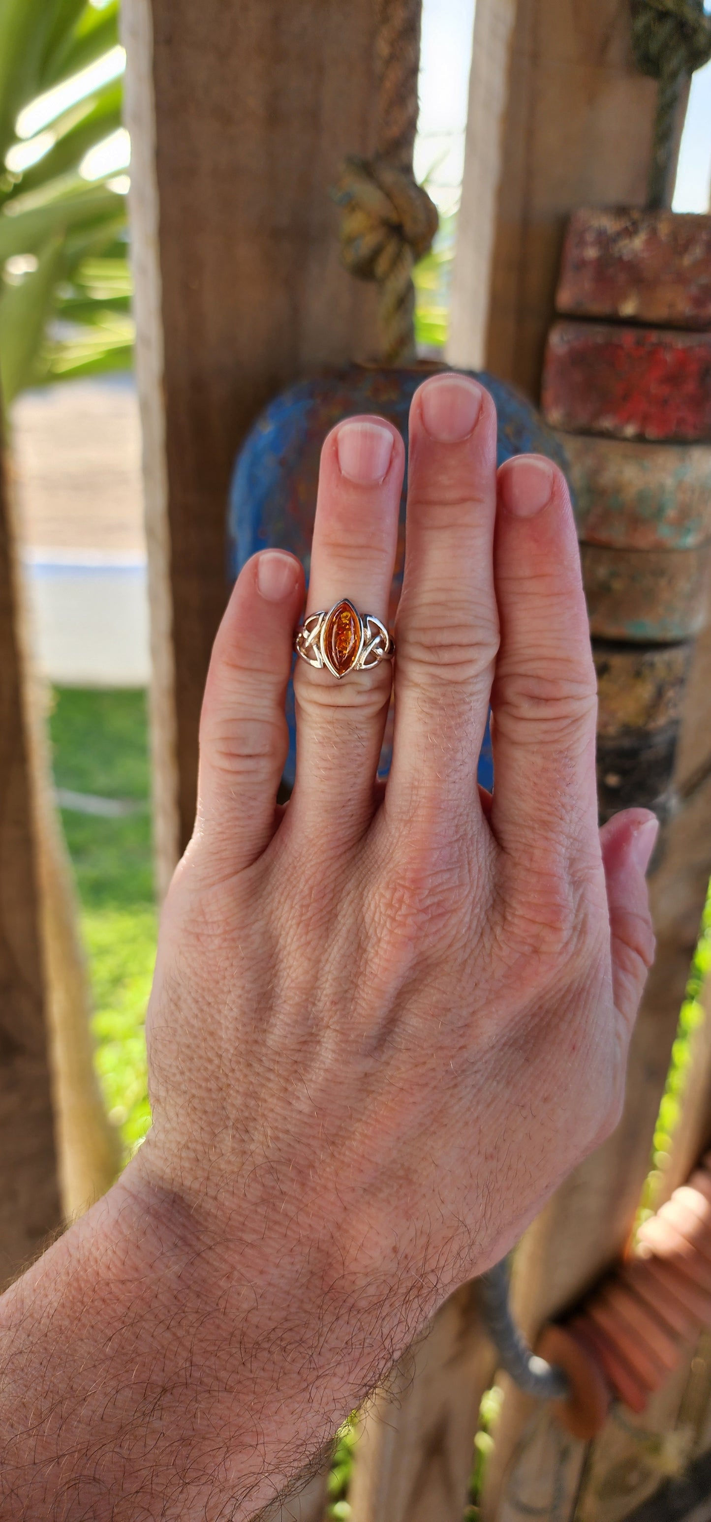 This sterling silver ring is a masterpiece of both elegance and symbolism, its design rooted in ancient Celtic tradition. At the heart of the piece rests a marquise-cut Baltic amber cabochon, its golden depths shimmering like liquid sunlight.