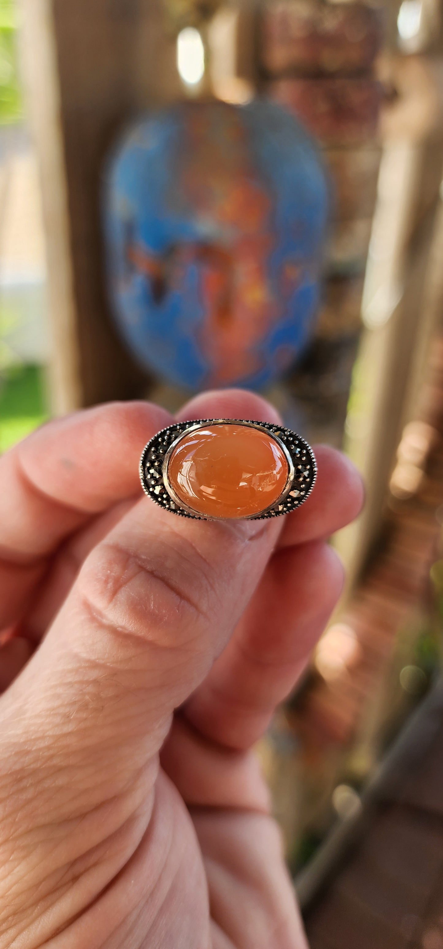 This chunky sterling silver statement dress ring is a striking fusion of bold design and vintage charm, exuding an air of mystery and elegance. At its heart lies a mesmerizing oval orange moonstone cabochon, set securely in a smooth bezel setting.