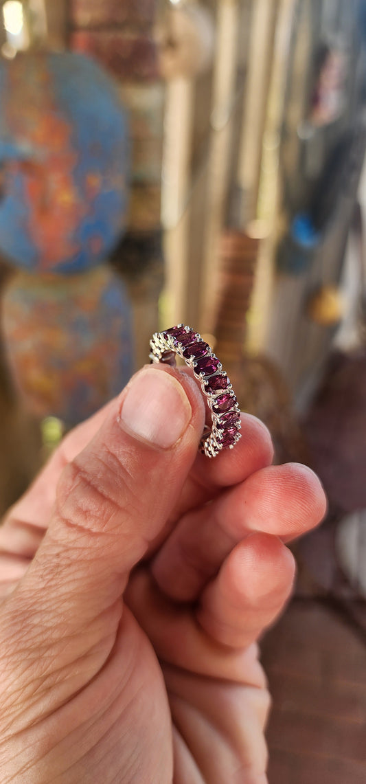This sterling silver full eternity ring is a dazzling display of deep, rich purple rhodolite garnets, meticulously claw-set in an endless circle of brilliance.