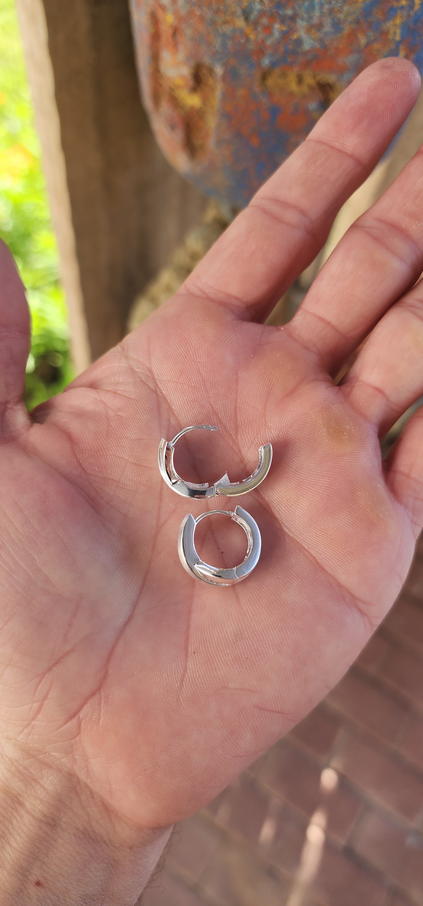 These stunning sterling silver huggie earrings are a masterpiece contemporary design. Their form exudes sophistication, featuring an X-shaped cross-over pattern that seamlessly combines polished silver with a soft, brushed texture.