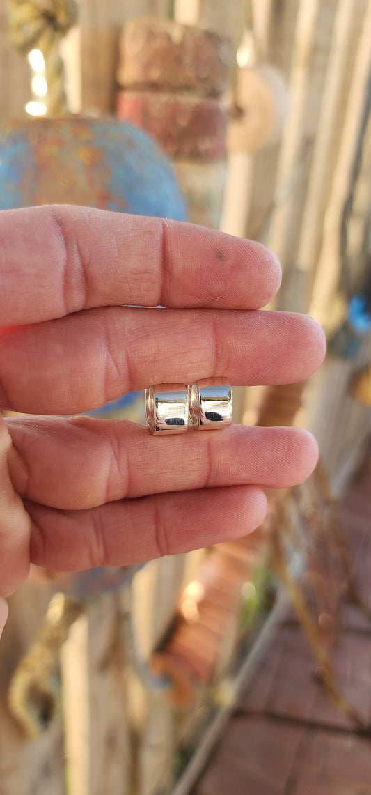 These sterling silver huggie earrings are a masterclass in modern minimalism, sculpted in a bold rounded-rectangular shape that hugs the ear with contemporary charm.