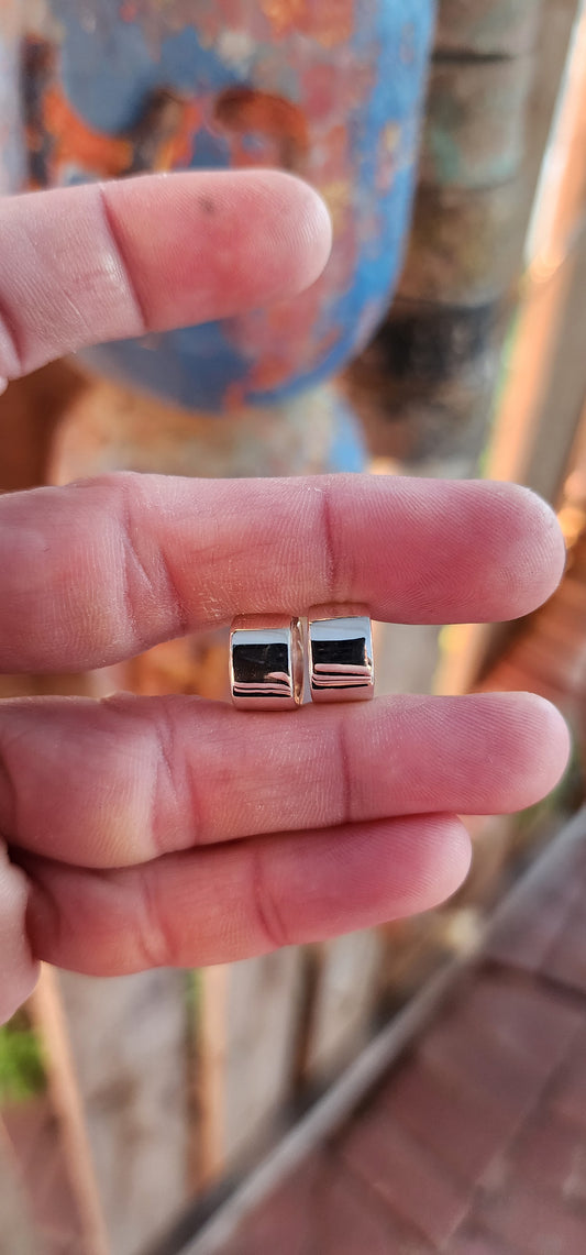 These sterling silver huggie earrings are a masterclass in modern minimalism, sculpted in a bold rounded-rectangular shape that hugs the ear with contemporary charm.