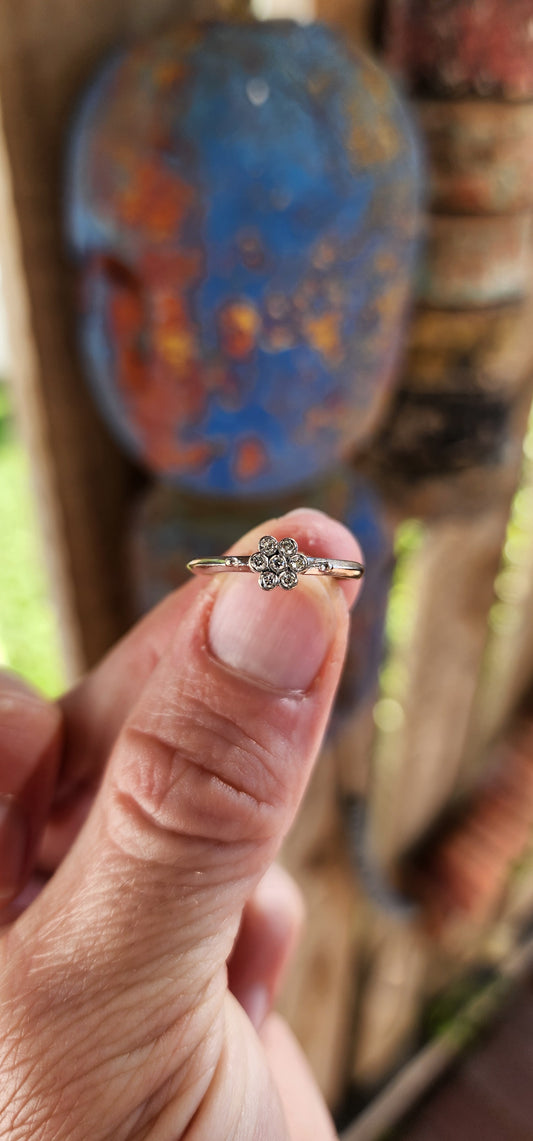 A timeless bloom of elegance—this vintage beauty is the epitome of delicate grace. Crafted in solid 18ct white gold, this charming ring features a petite flower cluster formed from seven small round cut white diamonds .