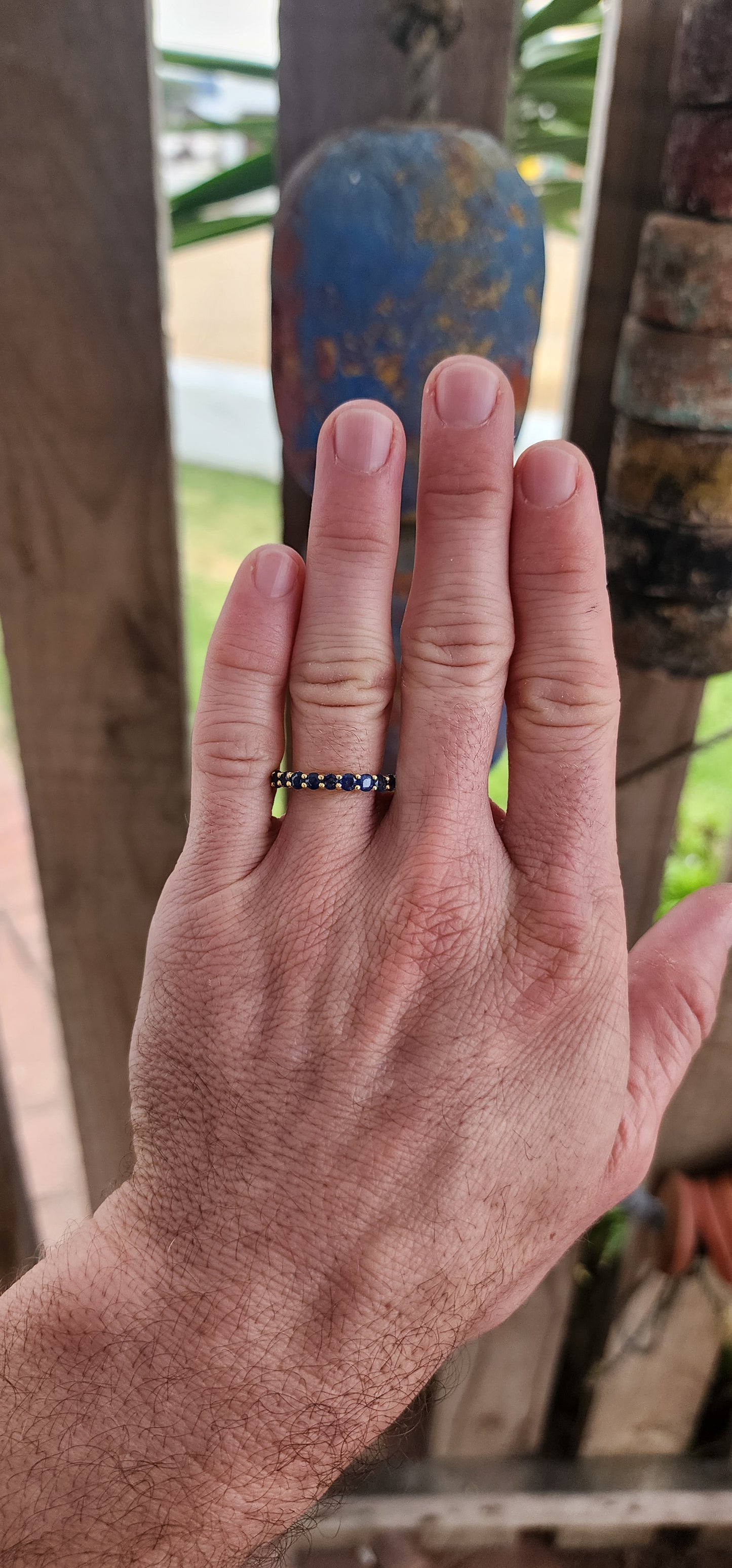 This unisex full eternity ring is masterfully forged in sterling silver and luxuriously plated in radiant yellow gold — a regal frame for 23 dazzling round-cut blue sapphires that shimmer like stars circling a golden sun.