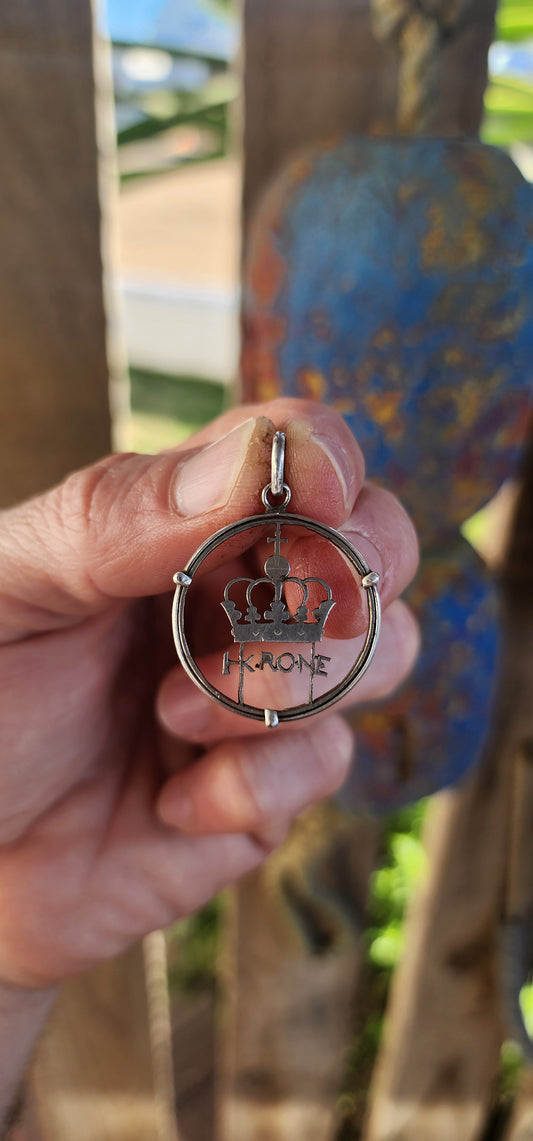 This striking piece is a clever fusion of history, craftsmanship, and upcycled artistry. Once an ordinary Norwegian 1 Krone coin, it has been masterfully transformed into a wearable tribute to regal simplicity and Scandinavian design heritage.