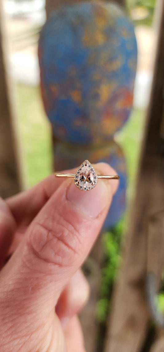 As delicate as the morning's first kiss of sunlight, this enchanting ring is a love letter in rose gold over sterling silver . Nestled at its heart is a pear-cut morganite gemstone, glowing softly like a drop of blushing dew caught at dawn.