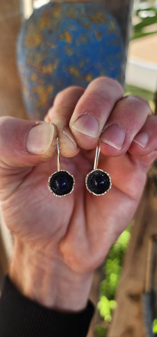 Artisan-crafted sterling silver drop earrings, each one features a richly textured, organic floral cup cradling a perfectly polished orb of deep royal blue lapis lazuli.
The lapis gleams with its signature golden flecks of pyrite.