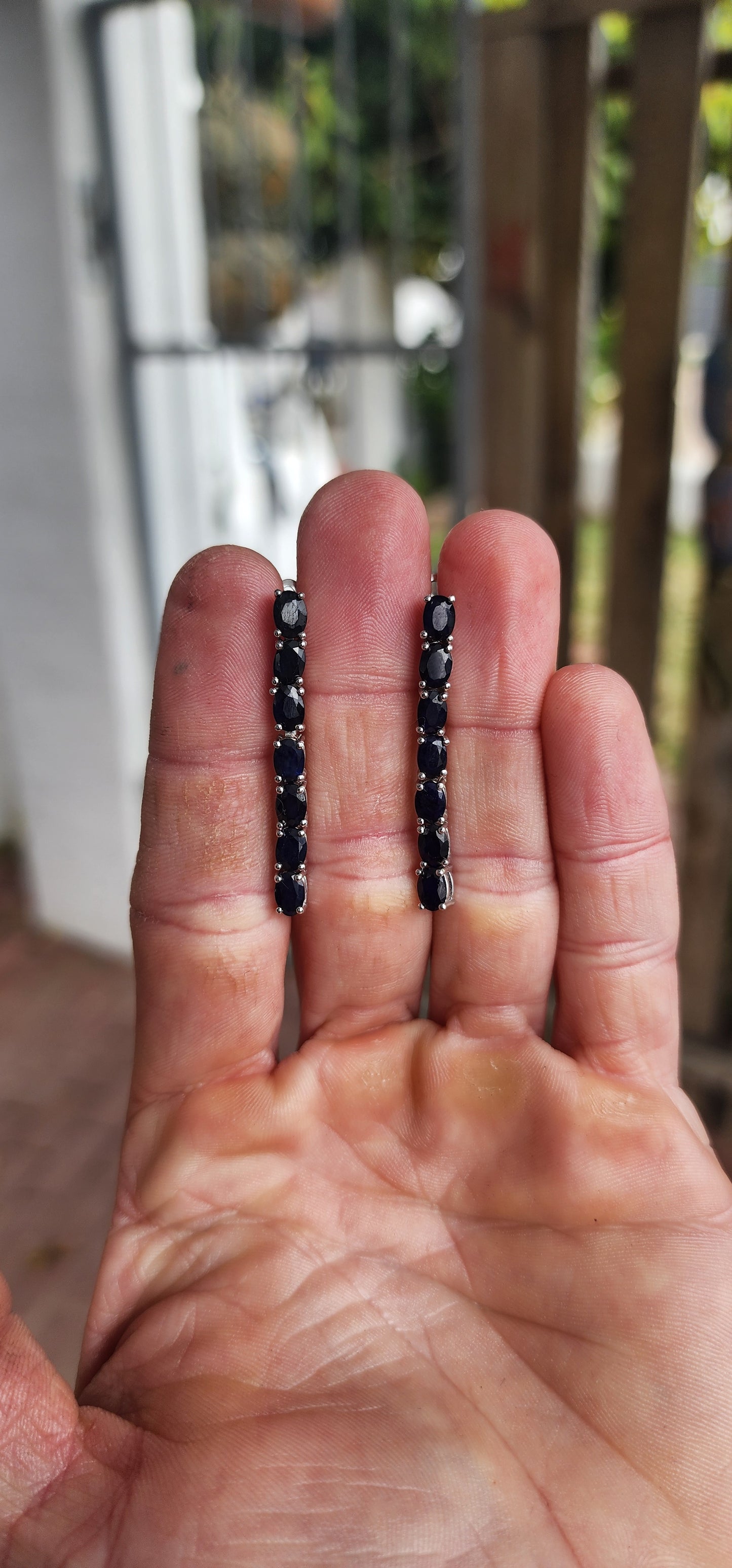 These sterling silver dangle earrings are designed to showcase the mysterious beauty of deep blue sapphires.