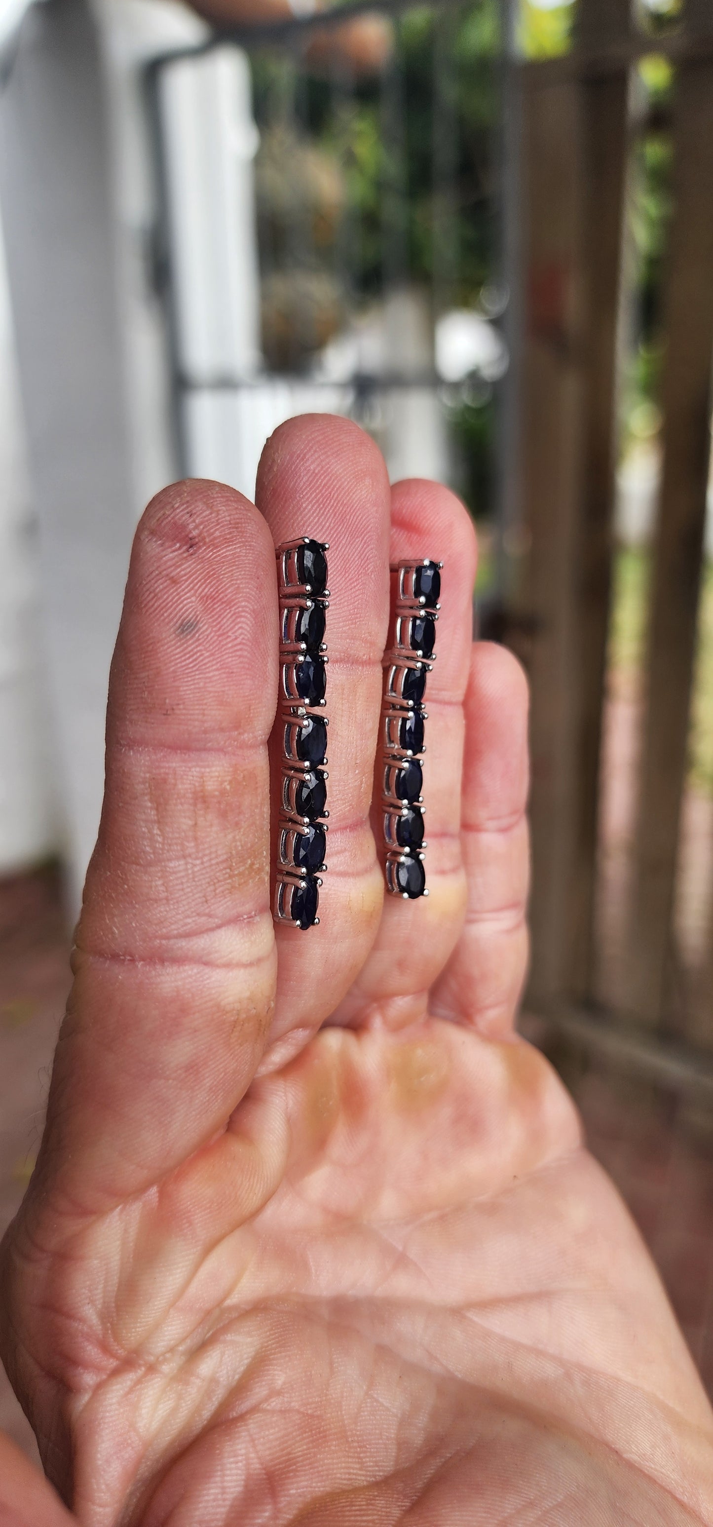 These sterling silver dangle earrings are designed to showcase the mysterious beauty of deep blue sapphires.