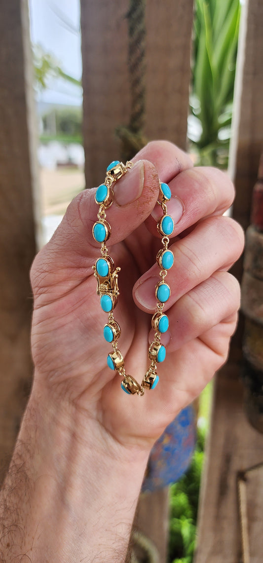 This beautiful tennis bracelet is crafted in sterling silver and finished with rich 18ct yellow gold plating, giving it a warm, luxurious glow. It features a row of 16 oval sleeping beauty turquoise cabochons.