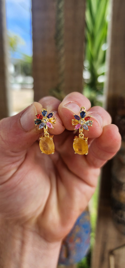 Fairytale Blossoms in Golden Light.
Crafted in sterling silver and plated in luxurious 18ct yellow gold, each earring begins with a radiant floral bloom, lovingly composed of colorful sapphires in playful pear and marquise cuts.