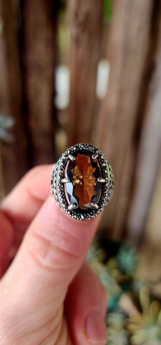 This bold and beautifully crafted sterling silver cocktail ring channels the grandeur of antique jewelry design. At its heart lies a large and rare oval-cut champagne/brown topaz.