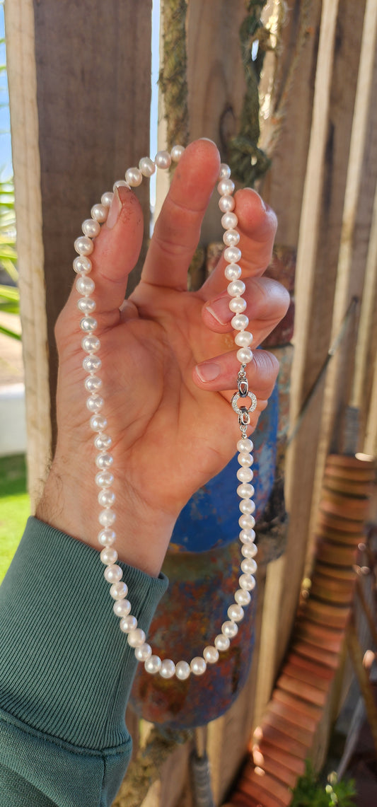 This elegant necklace is a classic strand of freshwater cultured pearls, a timeless jewel that has graced wardrobes for centuries.