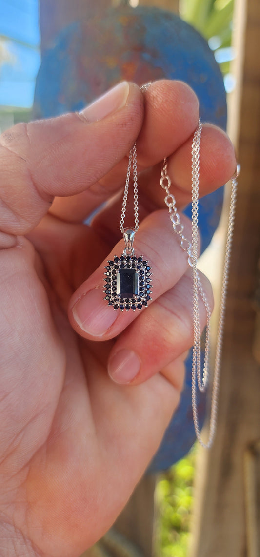 Elegant and timeless, this pendant features a richly saturated emerald-cut deep blue sapphire as its centerpiece, prong-set to capture and reflect light with depth and intensity.