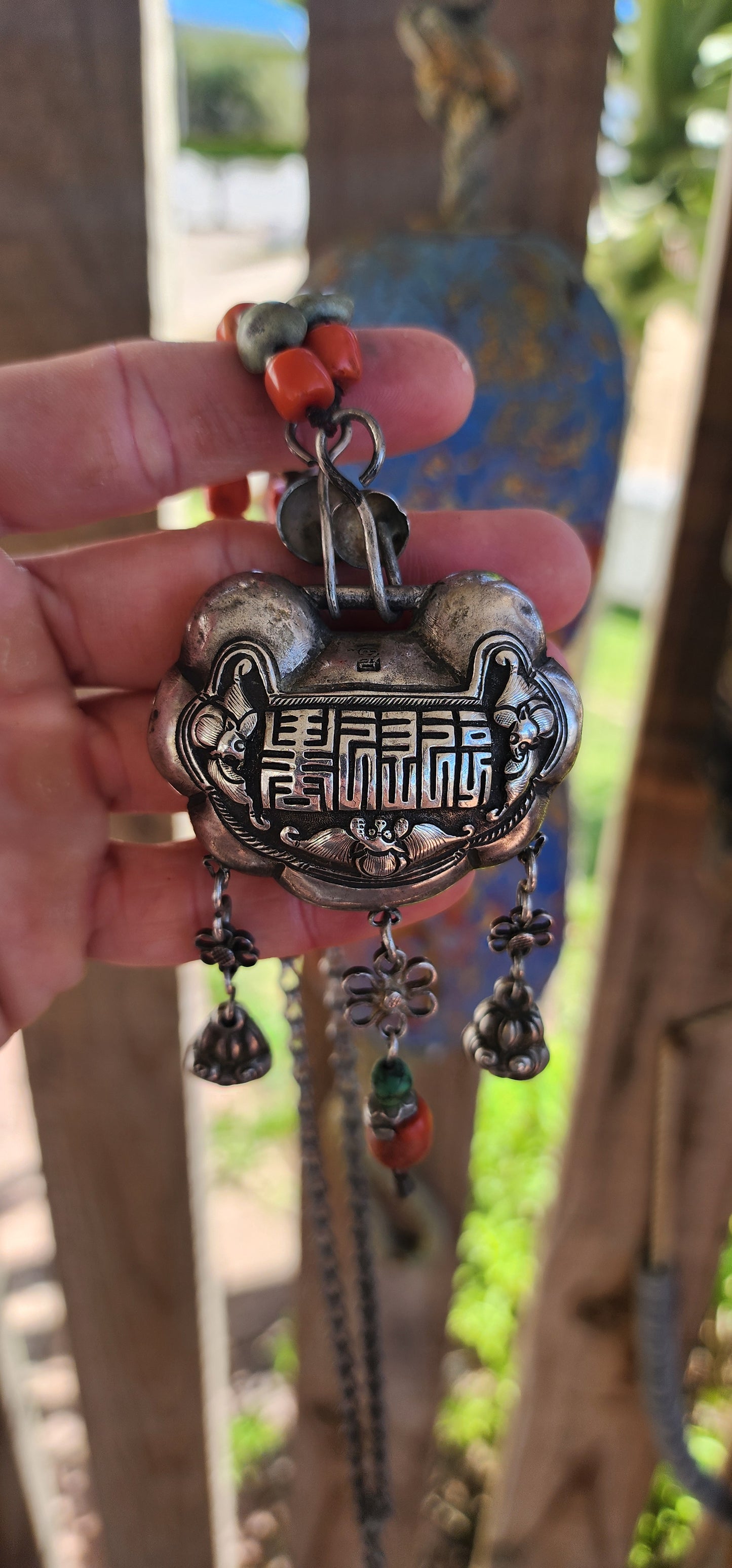An extraordinary and highly collectible antique Chinese Qing Dynasty sterling silver “Longevity Lock” rattle pendant necklace, lavishly embellished with turquoise and coral bead accents and ornate dangle charms.