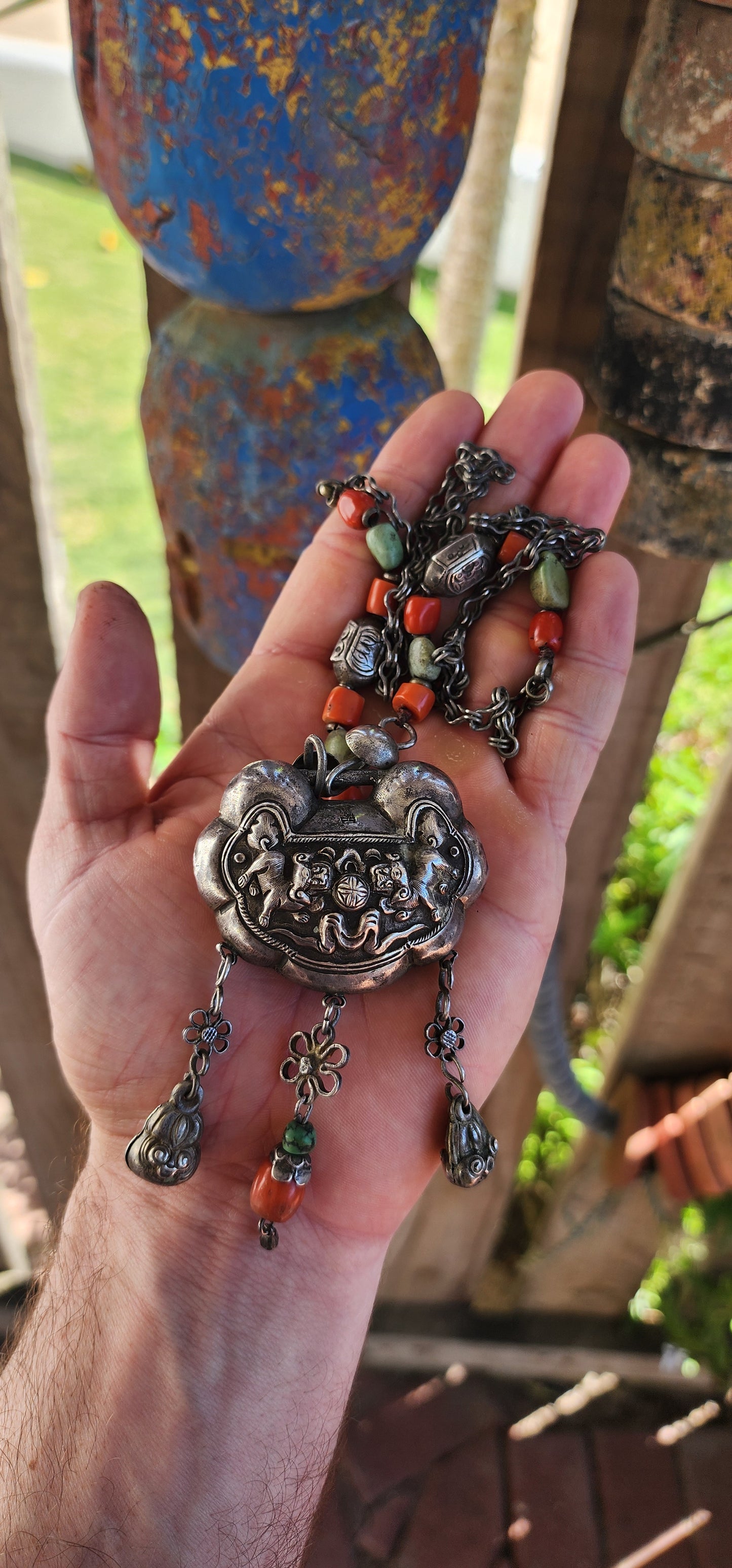 An extraordinary and highly collectible antique Chinese Qing Dynasty sterling silver “Longevity Lock” rattle pendant necklace, lavishly embellished with turquoise and coral bead accents and ornate dangle charms.
