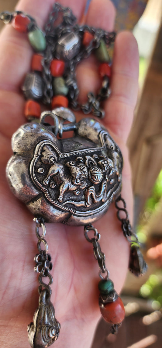 An extraordinary and highly collectible antique Chinese Qing Dynasty sterling silver “Longevity Lock” rattle pendant necklace, lavishly embellished with turquoise and coral bead accents and ornate dangle charms.