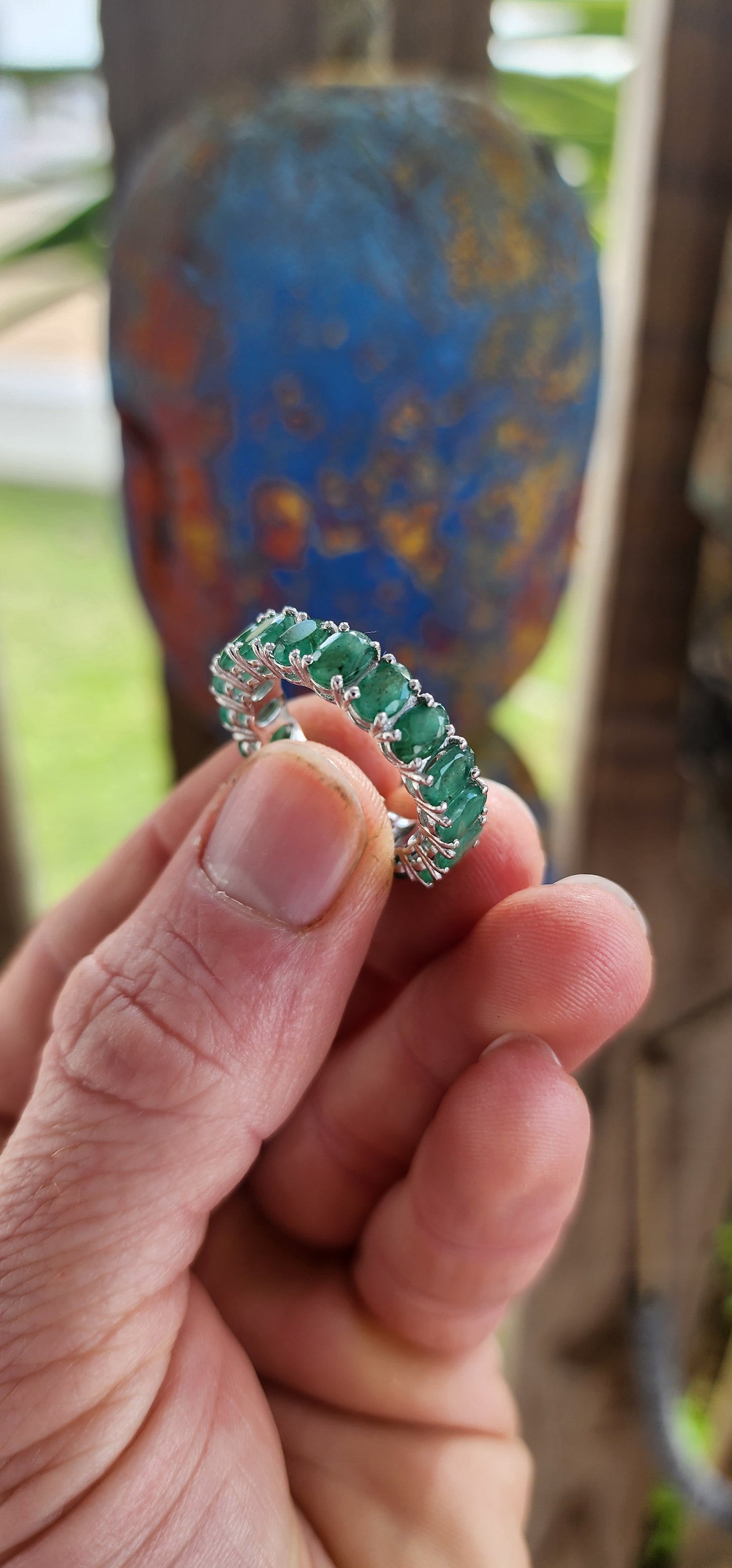 This glorious unisex sterling silver full eternity ring is a never-ending parade of 18 glowing oval-cut emeralds.