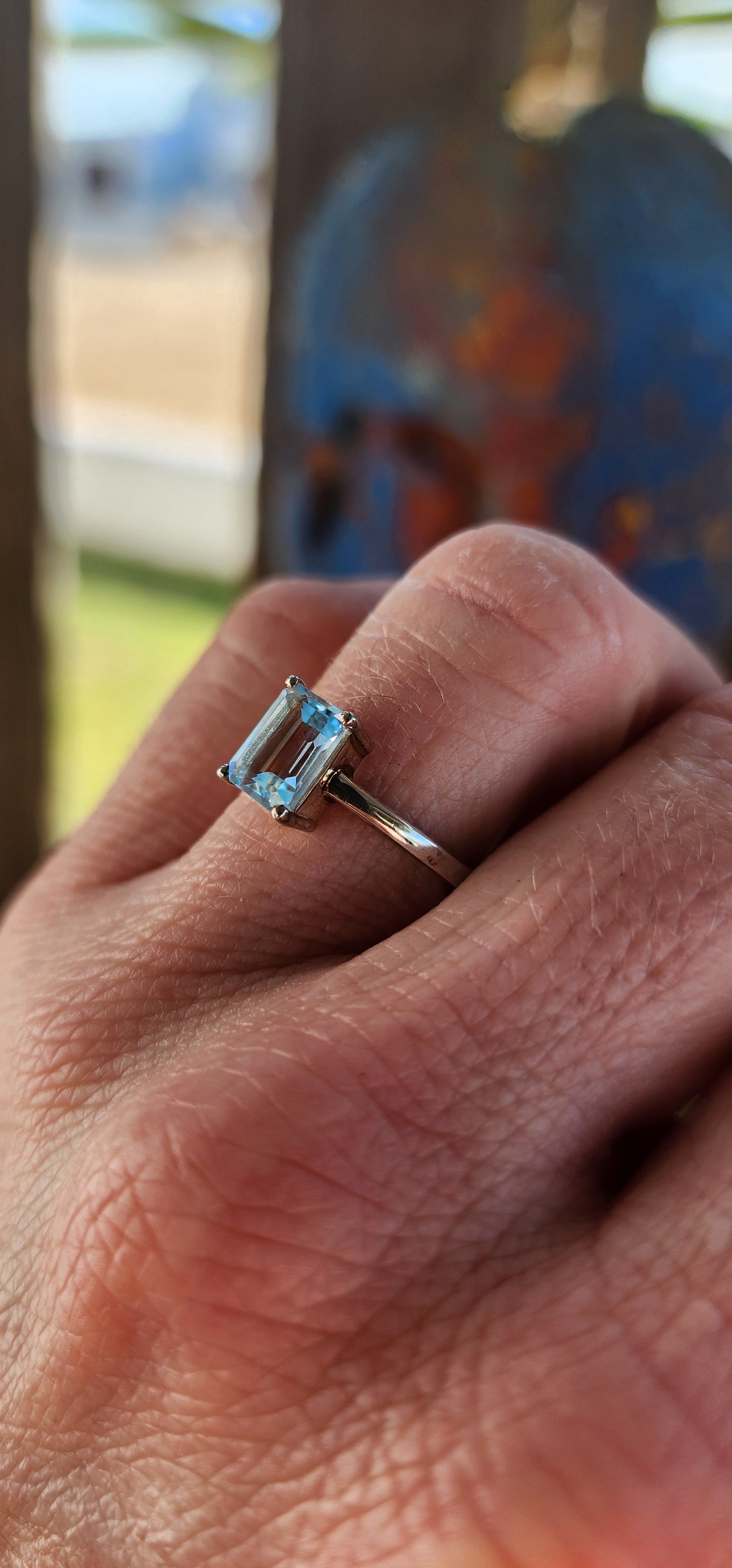 Beautifully crafted sterling silver solitaire ring.
At its heart lies a captivating emerald-cut sky blue topaz, held securely in a four-prong raised basket.
