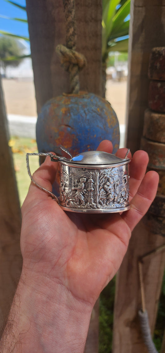 A beautiful example of Edwardian fascination with the “mystique of the East,” this circa 1902 hallmarked sterling silver mustard pot is richly cast in high relief with scenes of traditional life.
