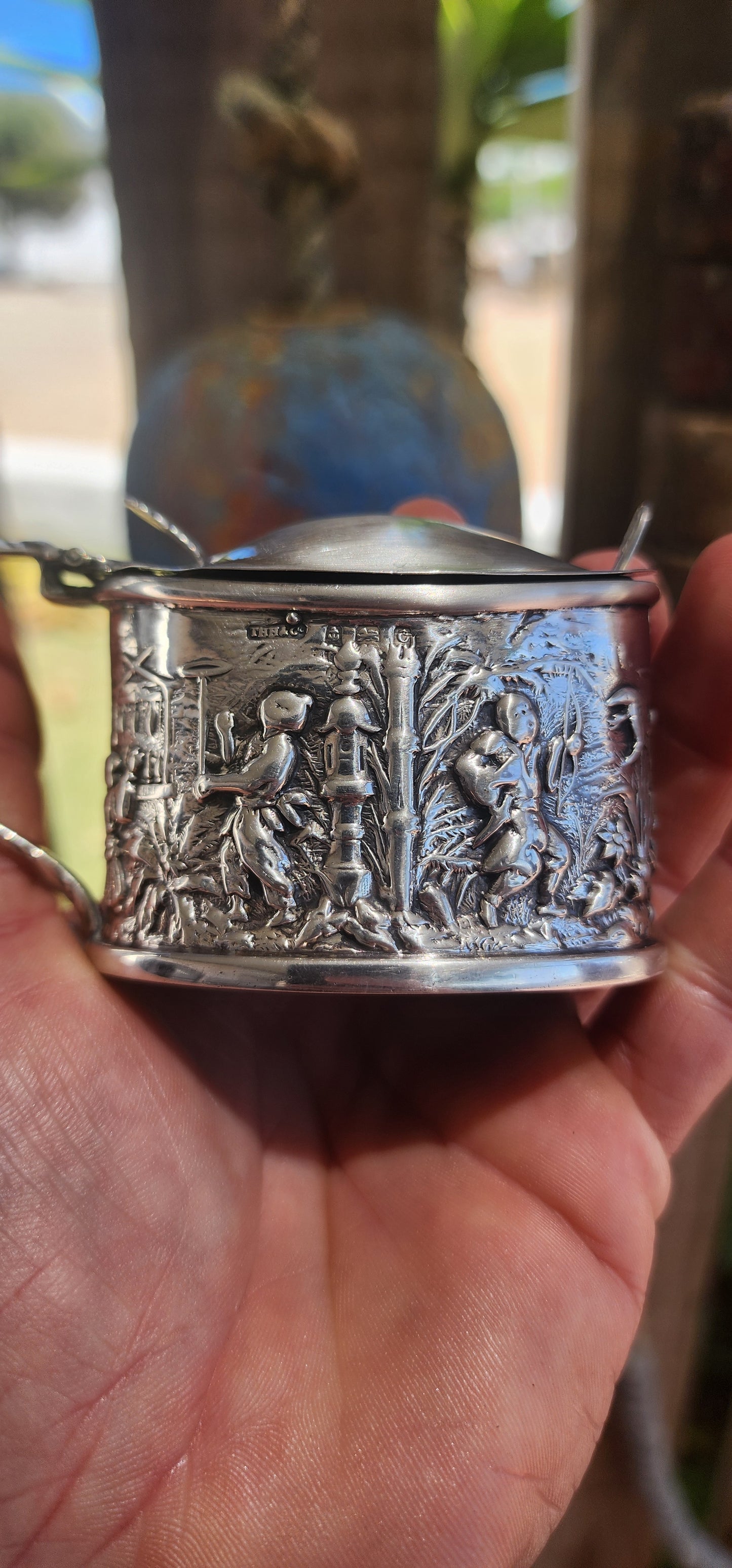 A beautiful example of Edwardian fascination with the “mystique of the East,” this circa 1902 hallmarked sterling silver mustard pot is richly cast in high relief with scenes of traditional life.