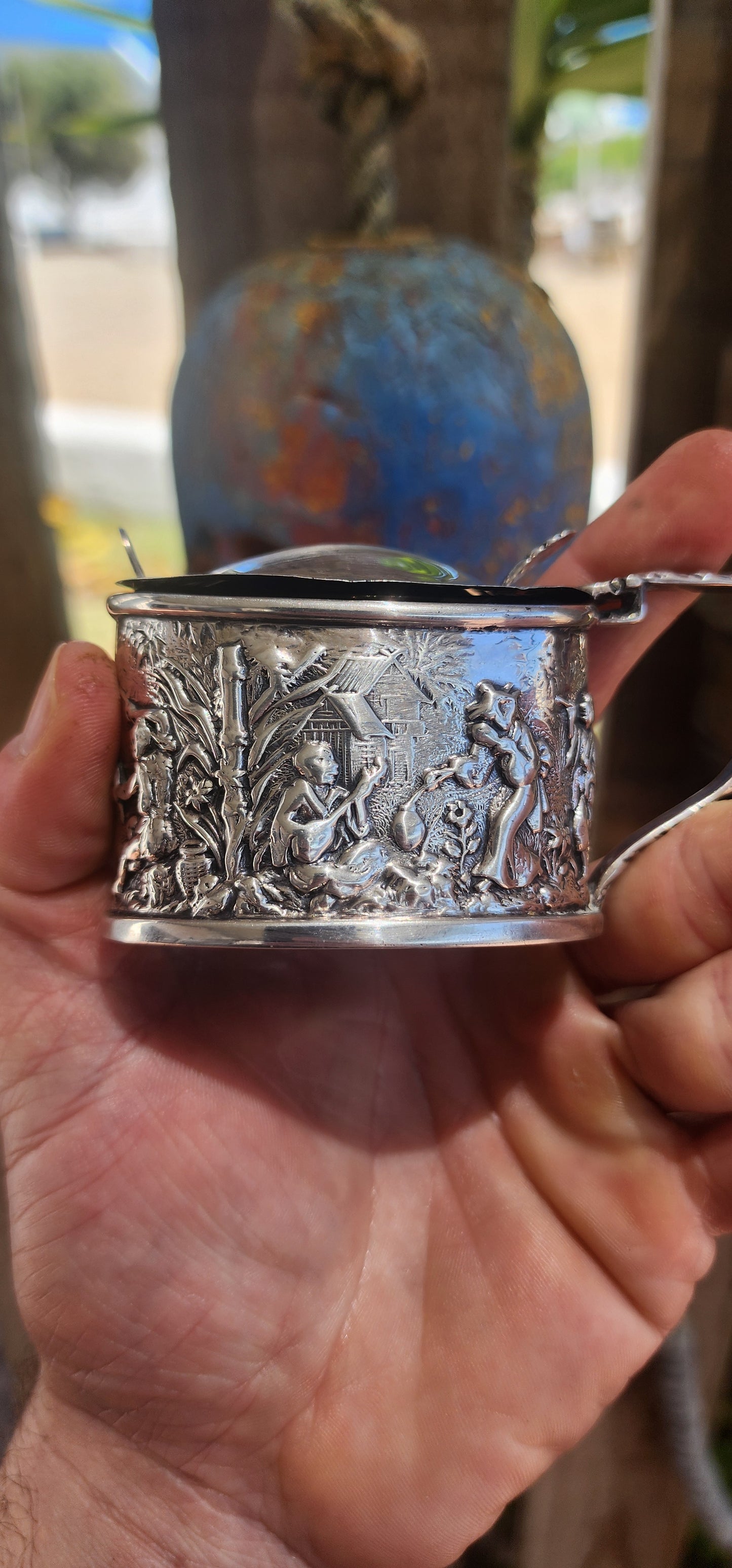 A beautiful example of Edwardian fascination with the “mystique of the East,” this circa 1902 hallmarked sterling silver mustard pot is richly cast in high relief with scenes of traditional life.