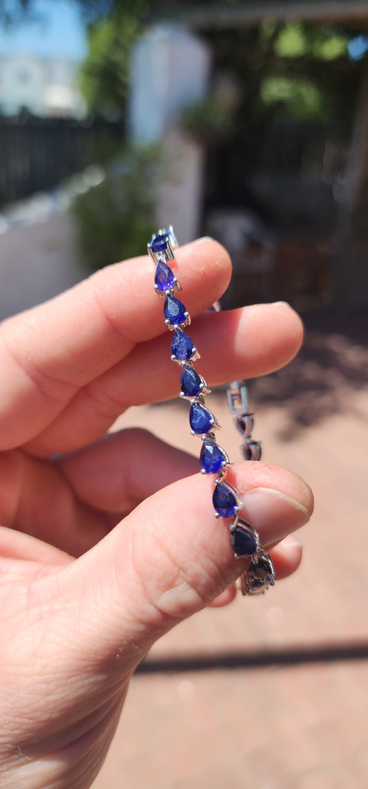 Breathtakingly beautiful sterling silver tennis bracelet, shimmering with 25 pear-cut deep-blue sapphires.
