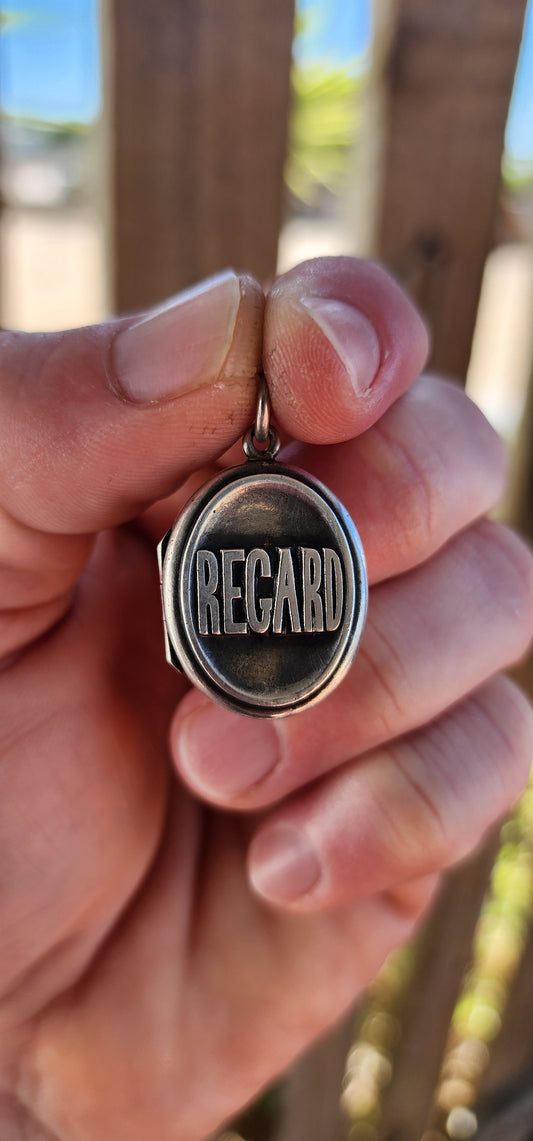 This marvelous antique Victorian-era sterling silver locket is crafted in a classic oval form, its front deeply embossed with the bold word “REGARD.”