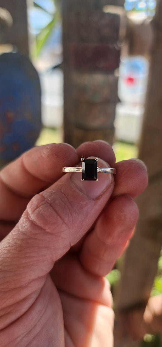 This striking sterling silver solitaire ring showcases a bold emerald-cut black onyx, elevated proudly in a sleek prong-set basket.