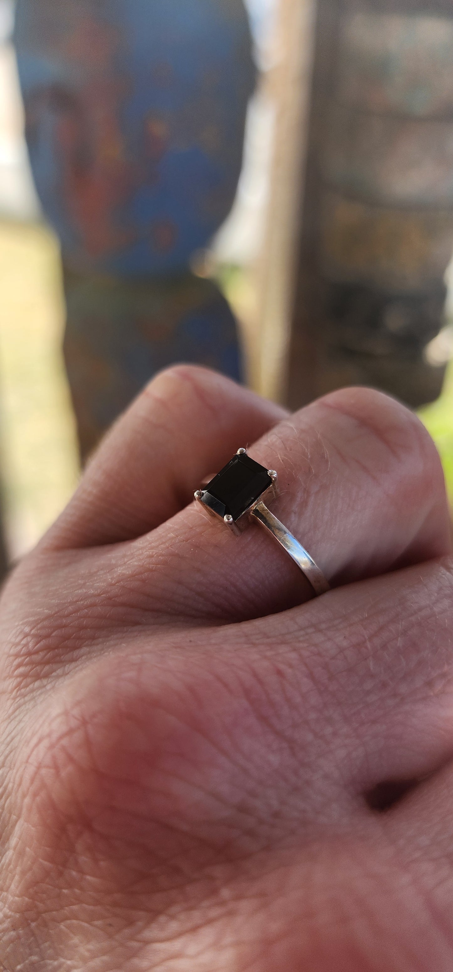This striking sterling silver solitaire ring showcases a bold emerald-cut black onyx, elevated proudly in a sleek prong-set basket.