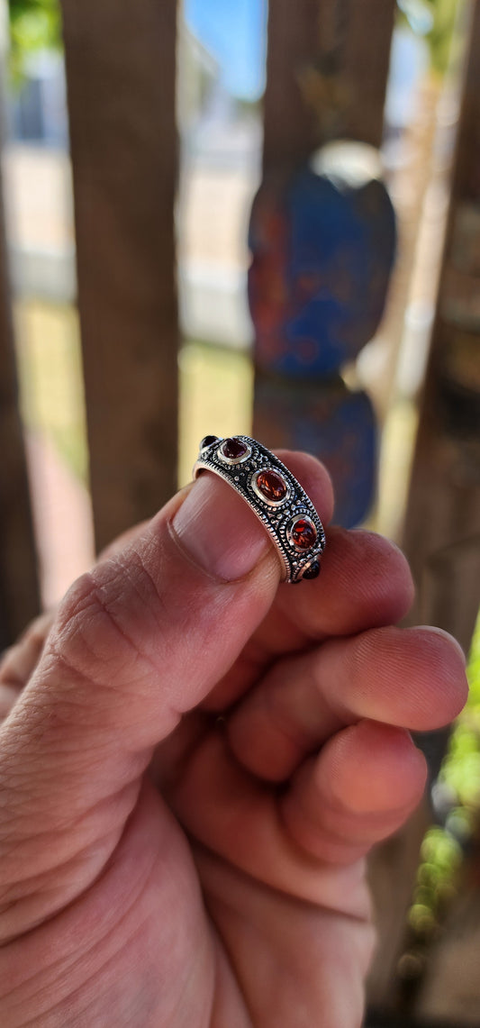 This fabulous unisex sterling silver full eternity ring is pure boho royalty — a band of endless fire wrapped around your finger. Set all the way around the entire circumference are 9 rich oval garnet cabochons.