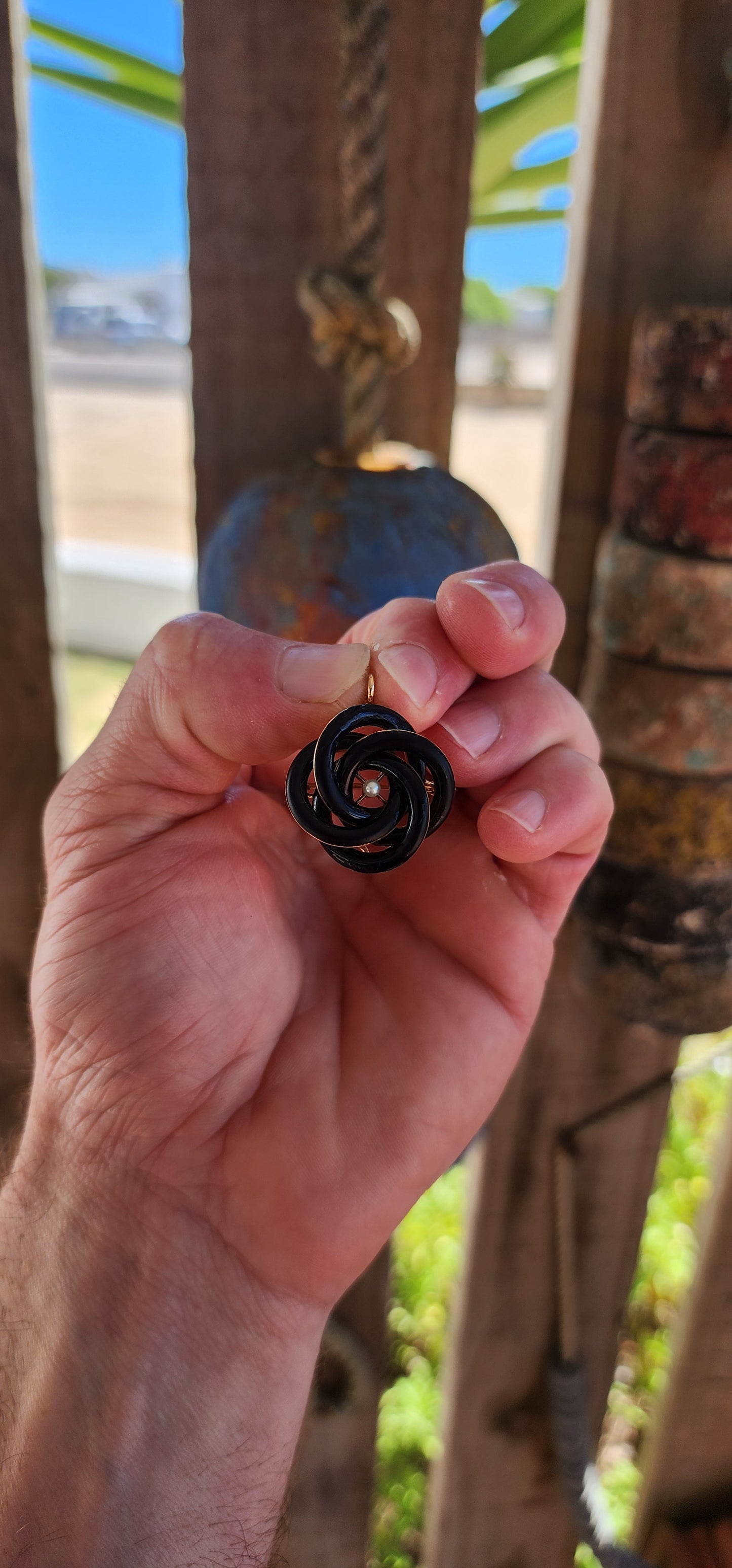 An exceptionally rare Antique Victorian mourning brooch / pendant, crafted in 10ct rosy gold, formed as a deeply symbolic eternity love knot, ebonised to a dramatic inky black enamel and centred with a single, luminous marine cultured pearl.