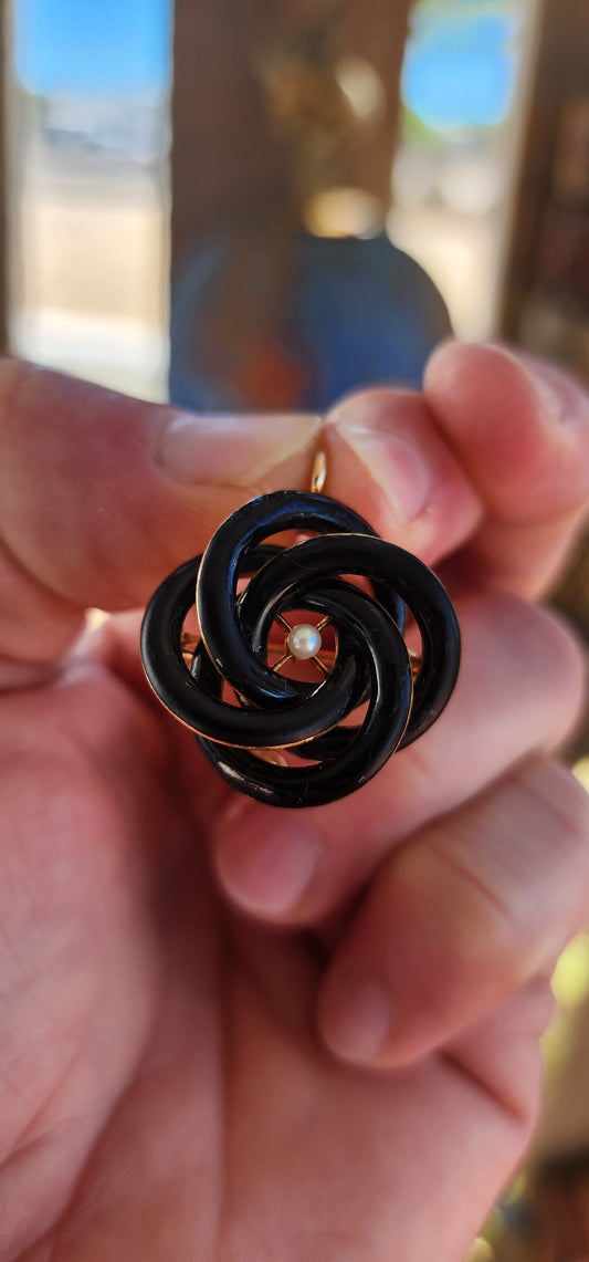 An exceptionally rare Antique Victorian mourning brooch / pendant, crafted in 10ct rosy gold, formed as a deeply symbolic eternity love knot, ebonised to a dramatic inky black enamel and centred with a single, luminous marine cultured pearl.