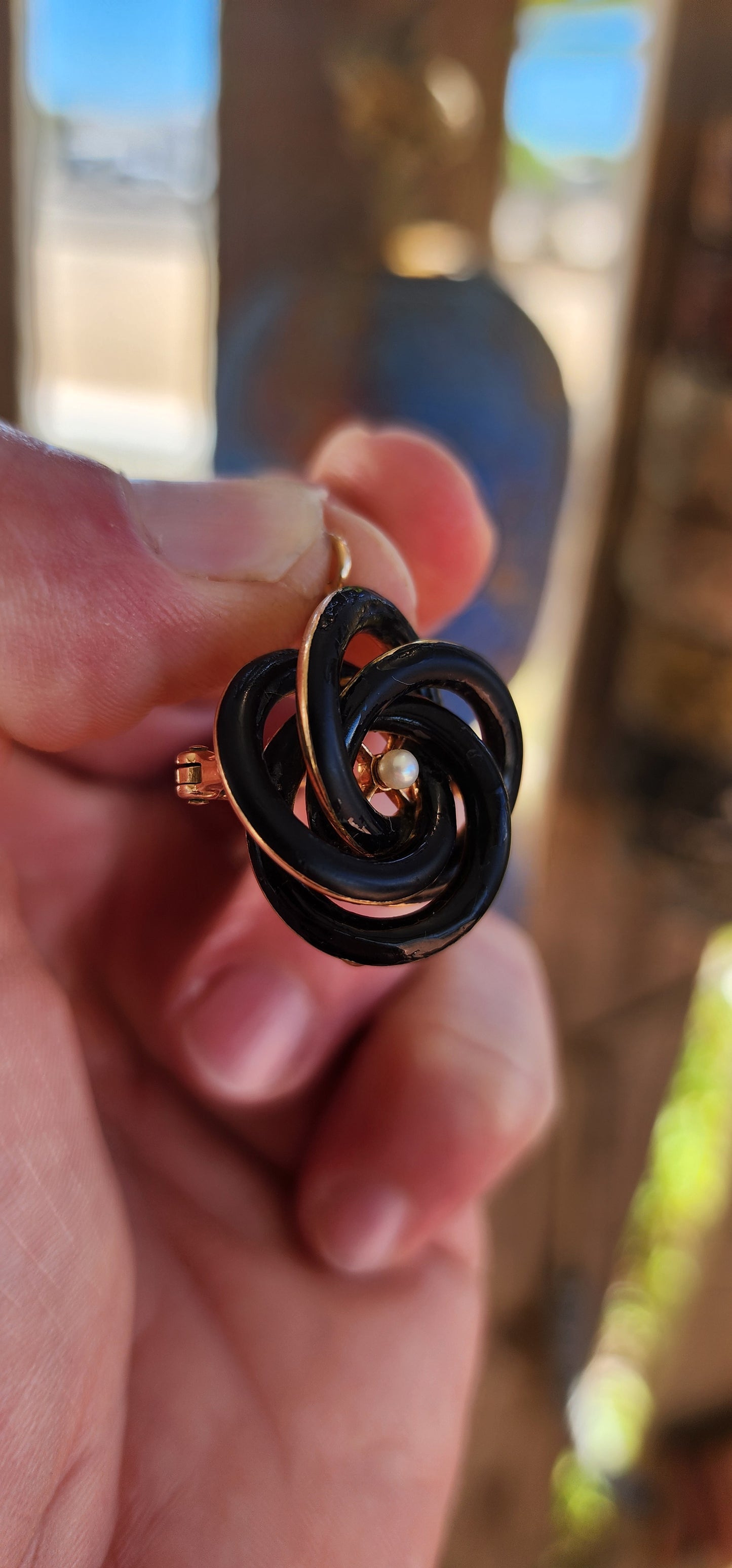 An exceptionally rare Antique Victorian mourning brooch / pendant, crafted in 10ct rosy gold, formed as a deeply symbolic eternity love knot, ebonised to a dramatic inky black enamel and centred with a single, luminous marine cultured pearl.