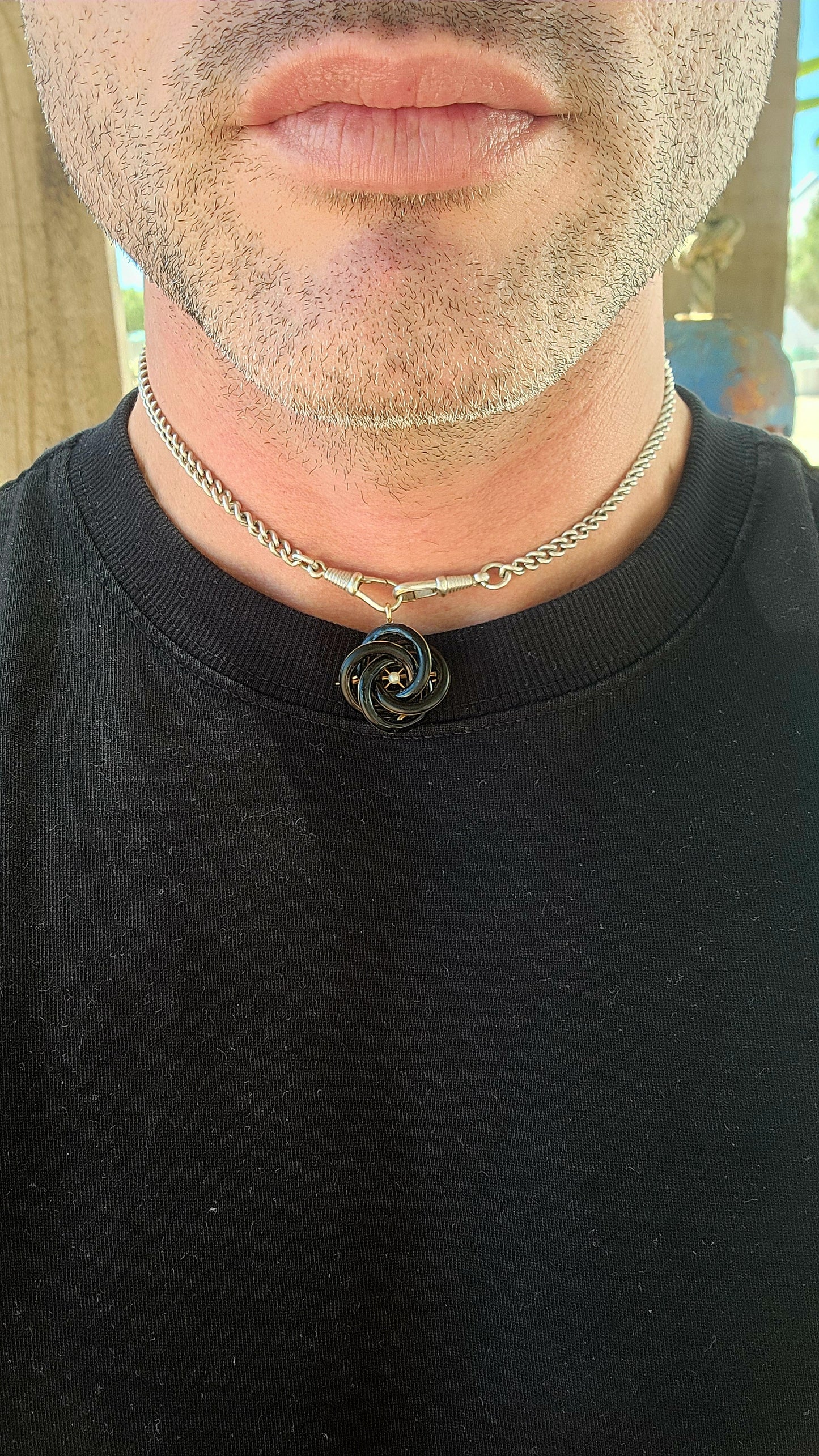 An exceptionally rare Antique Victorian mourning brooch / pendant, crafted in 10ct rosy gold, formed as a deeply symbolic eternity love knot, ebonised to a dramatic inky black enamel and centred with a single, luminous marine cultured pearl.