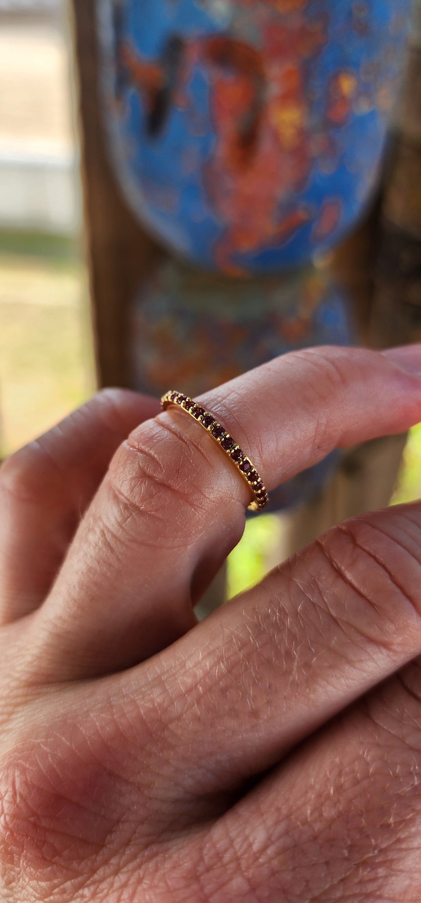A sterling silver full eternity stacking ring, luxuriously plated in 18ct yellow gold and adorned with a continuous circle of sparkling Purple/Red Rhodolite Garnets.