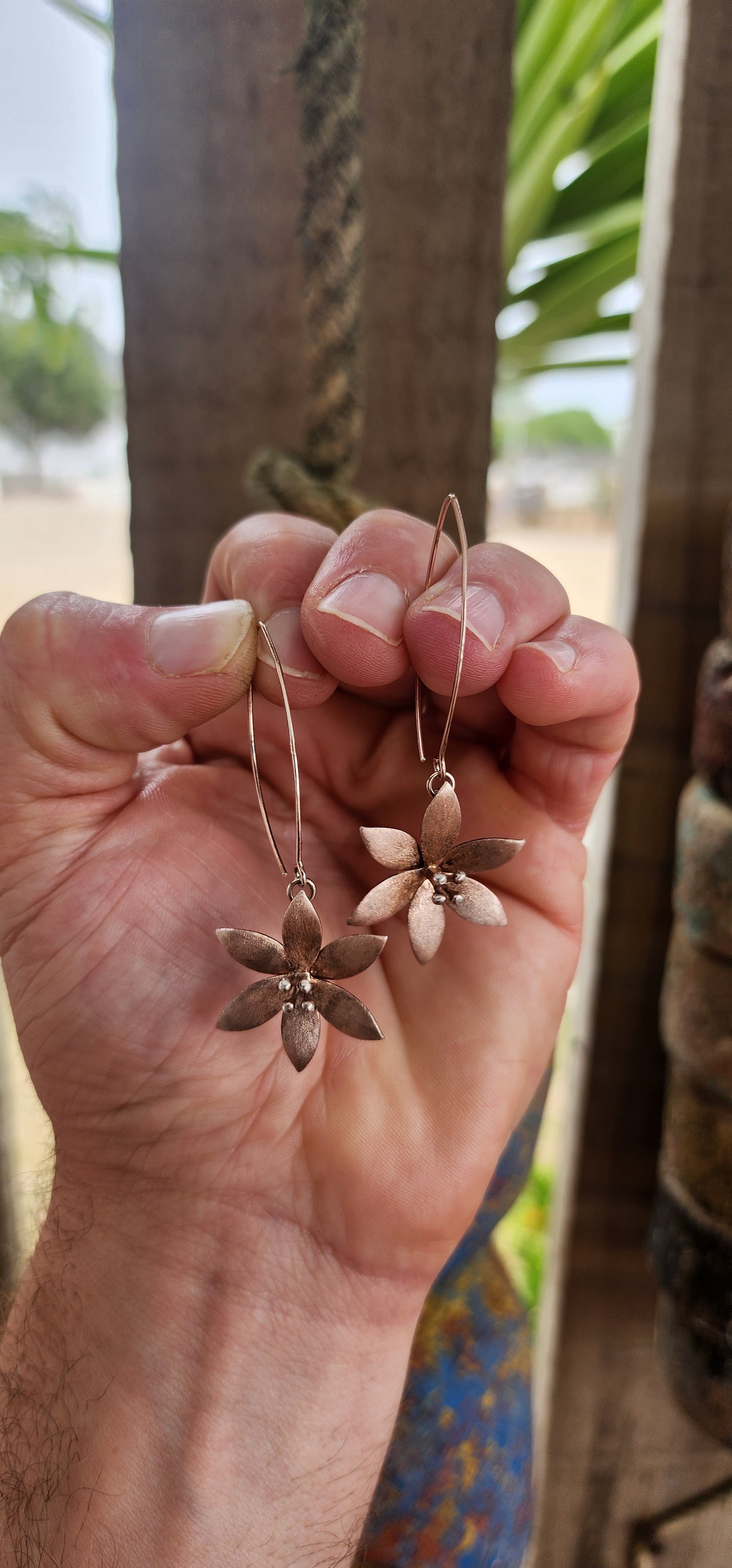 Crafted in sterling silver and finished with a subtle rose-gold wash, these flower drop earrings glow with a warm, romantic hue rather than a high-shine flash.