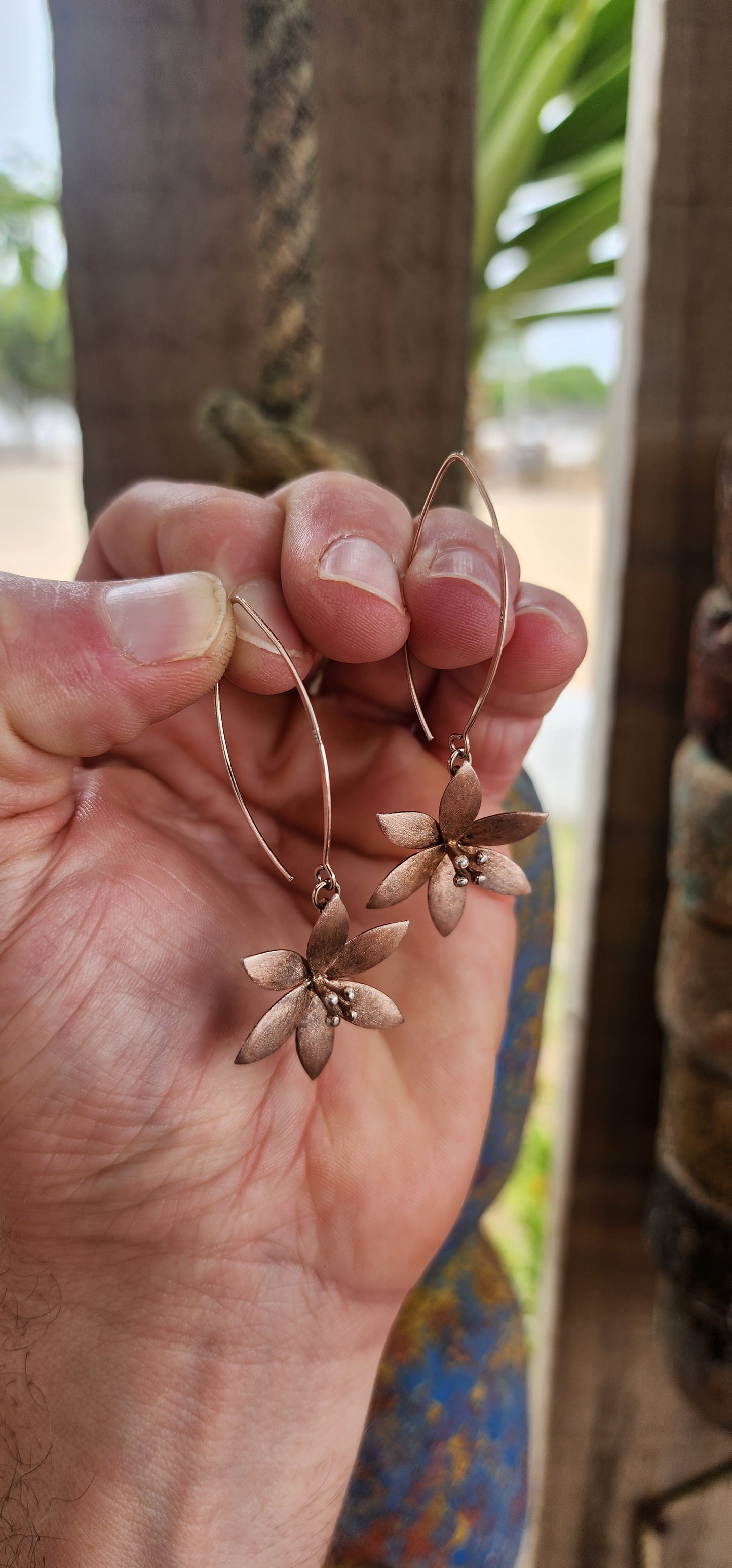 Crafted in sterling silver and finished with a subtle rose-gold wash, these flower drop earrings glow with a warm, romantic hue rather than a high-shine flash.